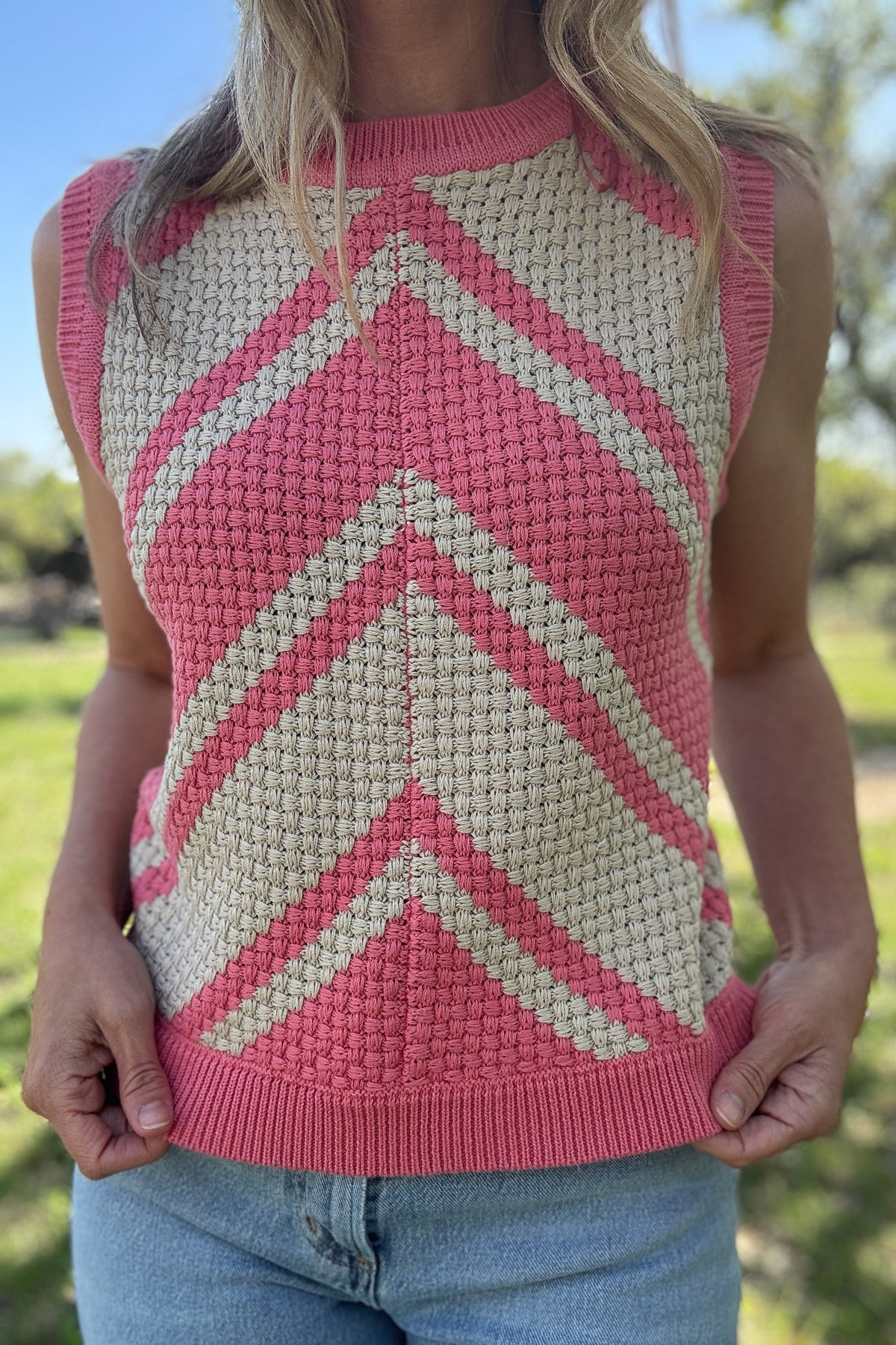 This bold basketweave knit tank is a standout piece with texture and color that pops. Made from 100% cotton, it’s soft, breathable, and perfect for warmer days. The sleeveless cut and crew neckline give it a classic shape, while the pink and cream chevron pattern adds just the right amount of fun. The basketweave knit adds structure without being heavy, making it an easy pick for everyday wear.