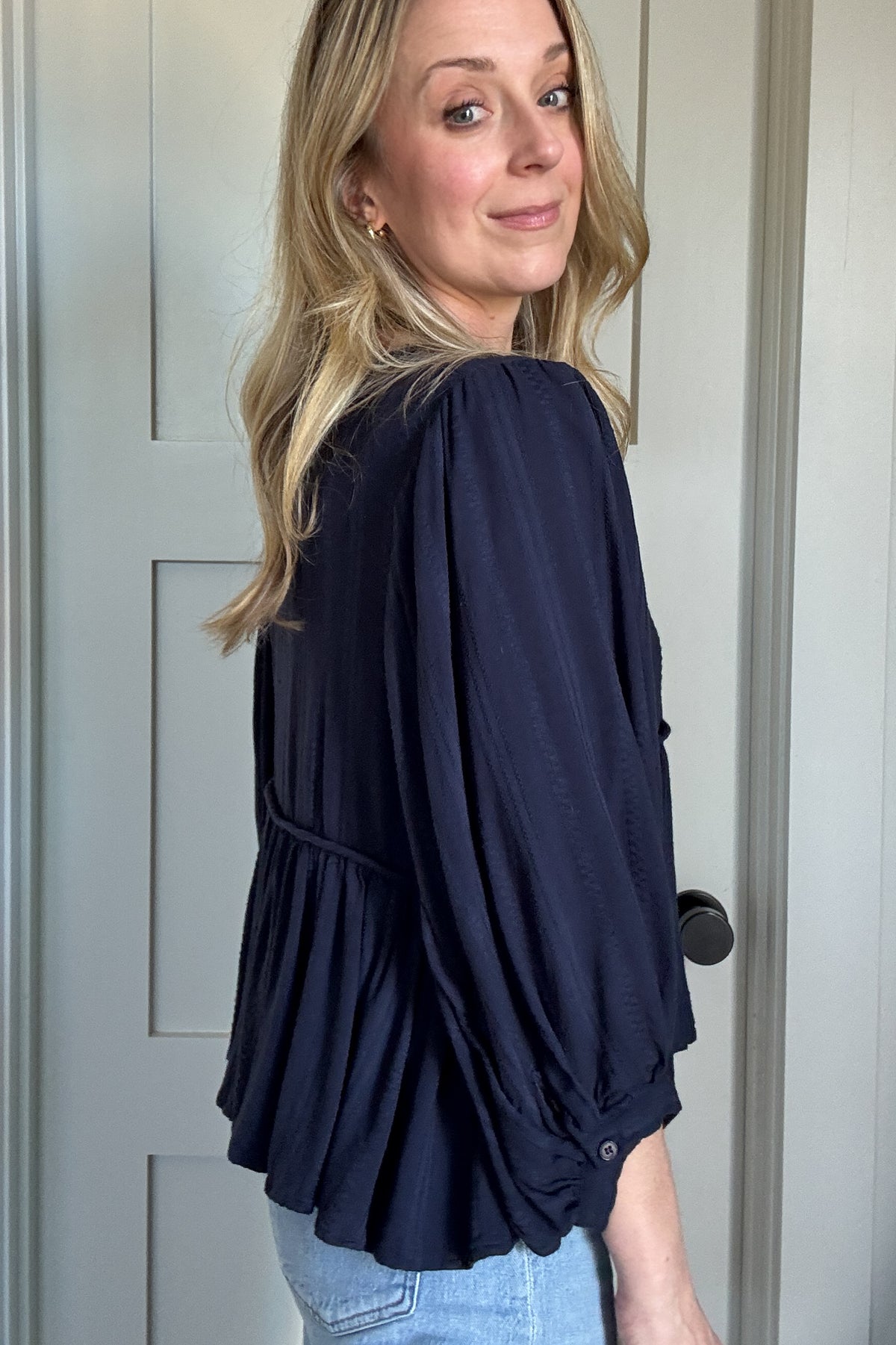 The Billowy Navy Textured Knit Blouse is a gorgeous, heavyweight piece that drapes beautifully and feels incredible on. It features a rich, deep navy hue with a subtle textured pattern, adding dimension to its effortless style. The relaxed fit is enhanced by a flattering V-neckline and delicate tie details. Voluminous sleeves with gathered cuffs add a touch of femininity, while the flowy, tiered silhouette gives it a chic, elevated look. Perfect for pairing with denim for an easy, stylish outfit.
