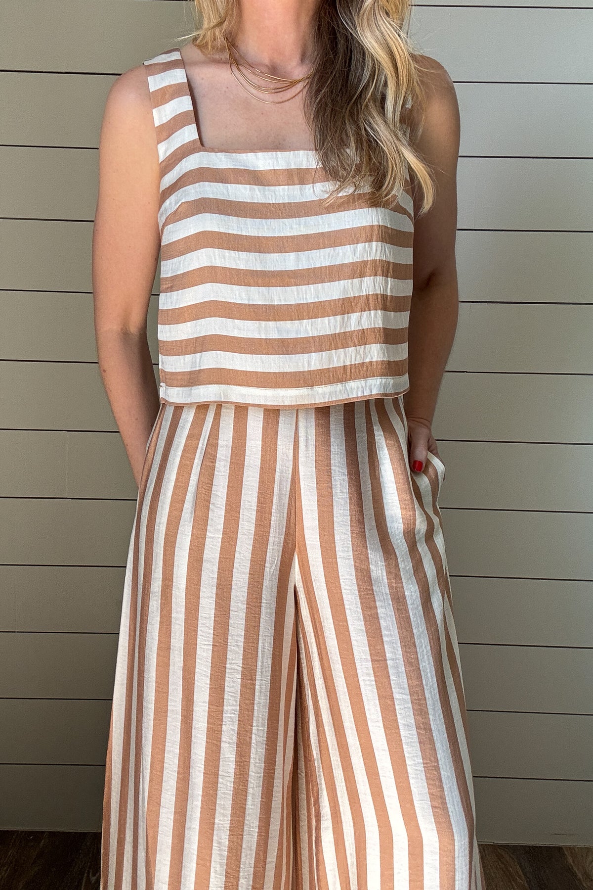 Effortless, breezy, and oh so fun! These full-length billowy pants from Traffic People bring all the flow with their vertical tan and cream stripes, side zipper, flattering flat front waistband, and comfy elastic back. They’ve got pockets (because who doesn’t love pockets?) and a soft lining for easy wear.
They pair with the striped shell top for a playful twist—horizontal stripes, a sleek square neckline, and a slip on design make it the perfect match. A little boho, a little classic, and totally effortle