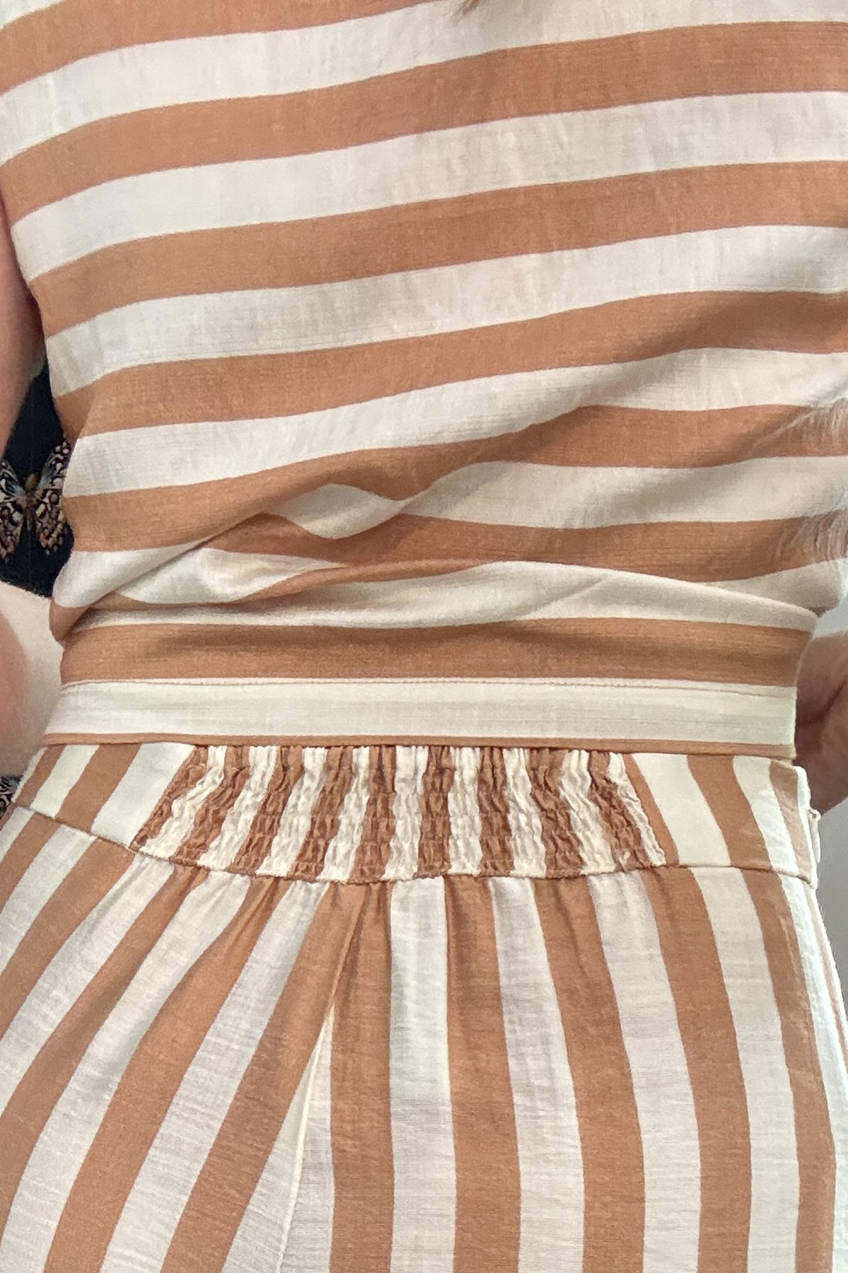 Effortless, breezy, and oh so fun! These full-length billowy pants from Traffic People bring all the flow with their vertical tan and cream stripes, side zipper, flattering flat front waistband, and comfy elastic back. They’ve got pockets (because who doesn’t love pockets?) and a soft lining for easy wear.
They pair with the striped shell top for a playful twist—horizontal stripes, a sleek square neckline, and a slip on design make it the perfect match. A little boho, a little classic, and totally effortle