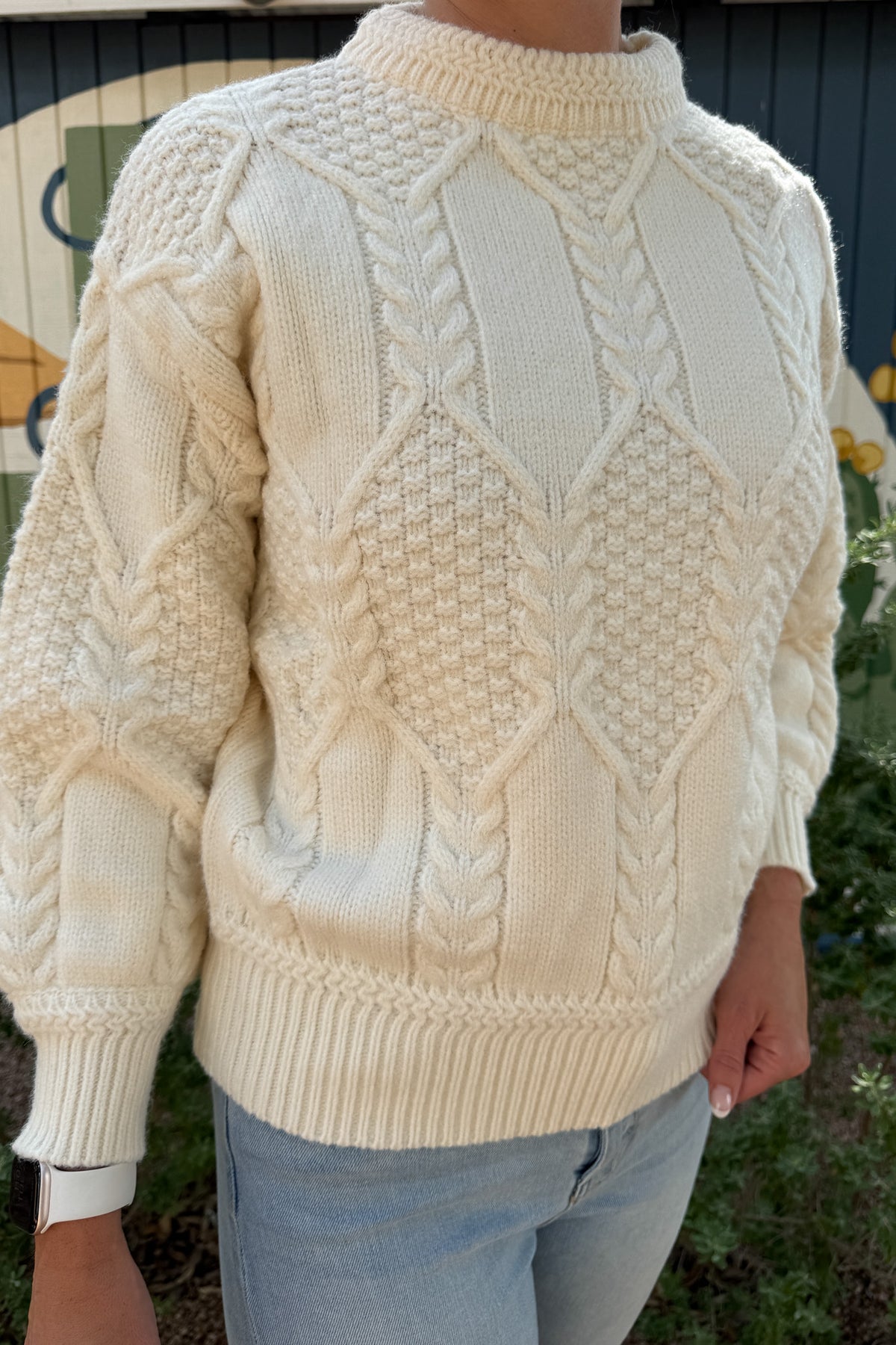 Classic cable knit gets a modern update in this ivory sweater. Designed with intricate knit detailing on the front and sleeves, it features a surprise open-back cutout that adds a chic twist to this timeless style. Soft, cozy, and versatile — it’s the perfect piece for effortless clothing and everyday wear.