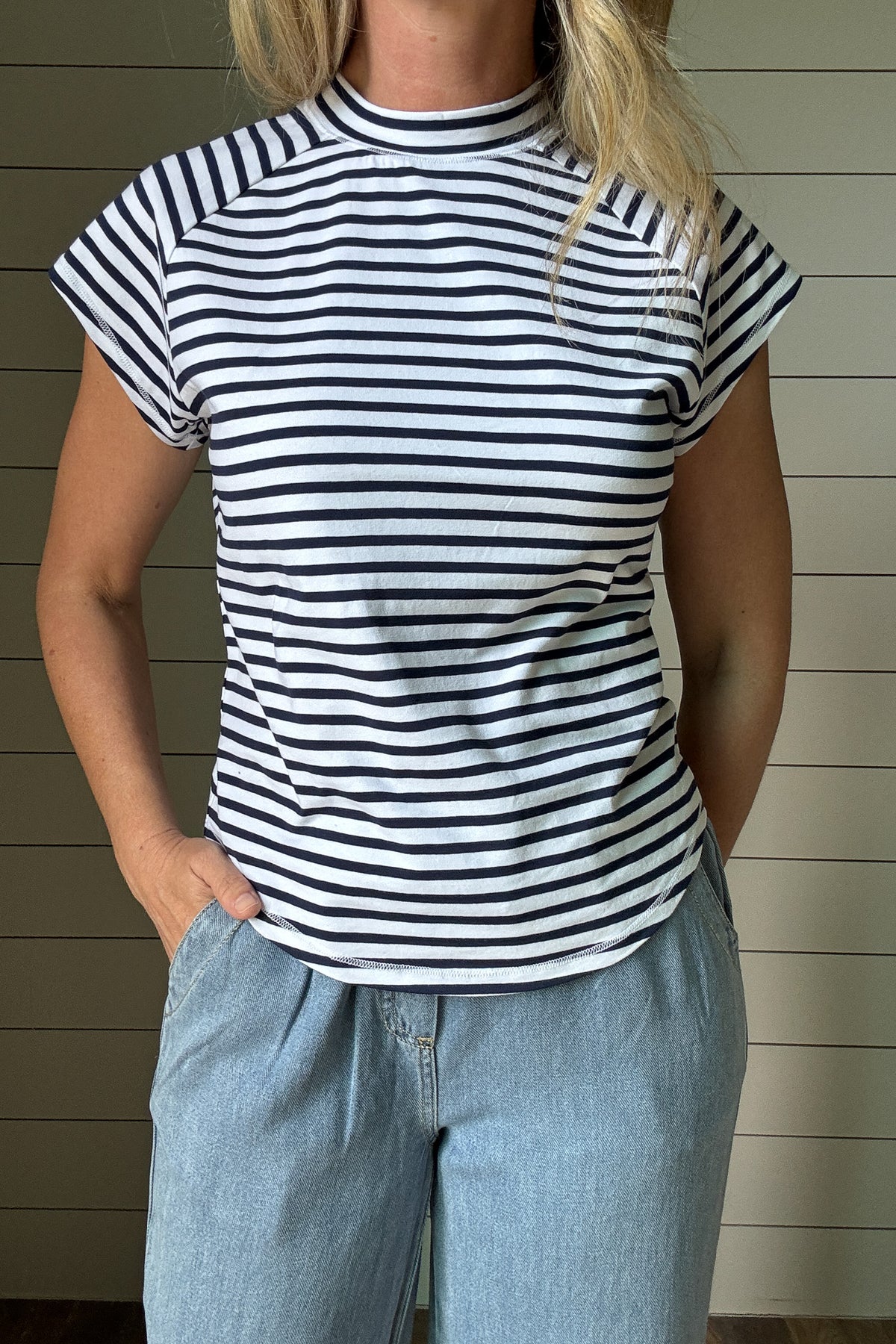  This striped high neck tee is a summer go-to. The navy and white stripe print feels fresh and classic, while the high neckline adds a modern touch. Made for everyday wear, it’s cut with a relaxed fit and a swooping hemline that gives it an easy, flattering shape. Whether you're heading out or staying casual, this tee is one you'll keep reaching for.