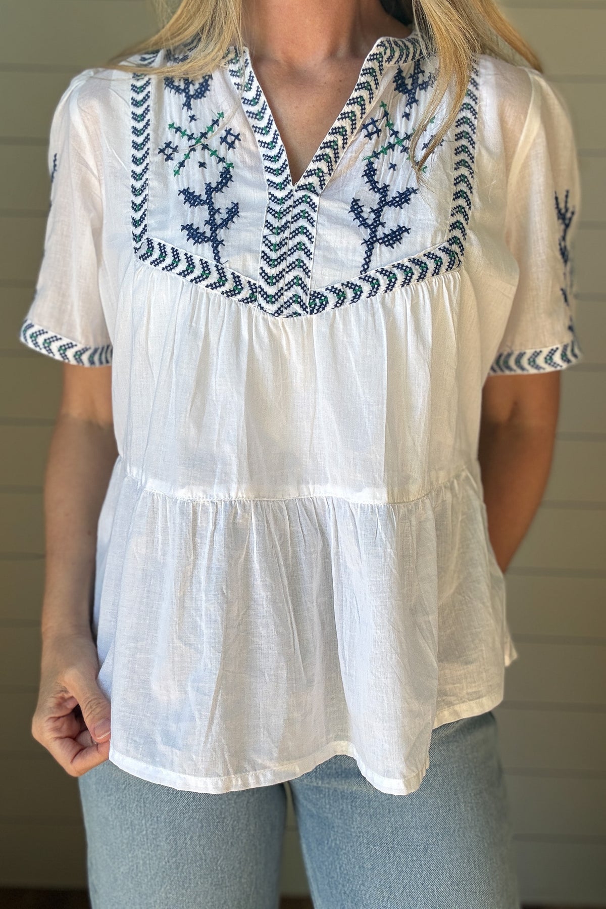 This breezy cotton blouse is all about easy charm. Made from 100% cotton, it's lightweight, breathable, and perfect for warm days. The hand-embroidered detail across the neckline, sleeves, and chest adds a special touch, each one slightly unique. It features a relaxed fit with soft gathers for a flowy shape that feels effortless and flattering. The split neckline and short sleeves keep the look casual and cool.