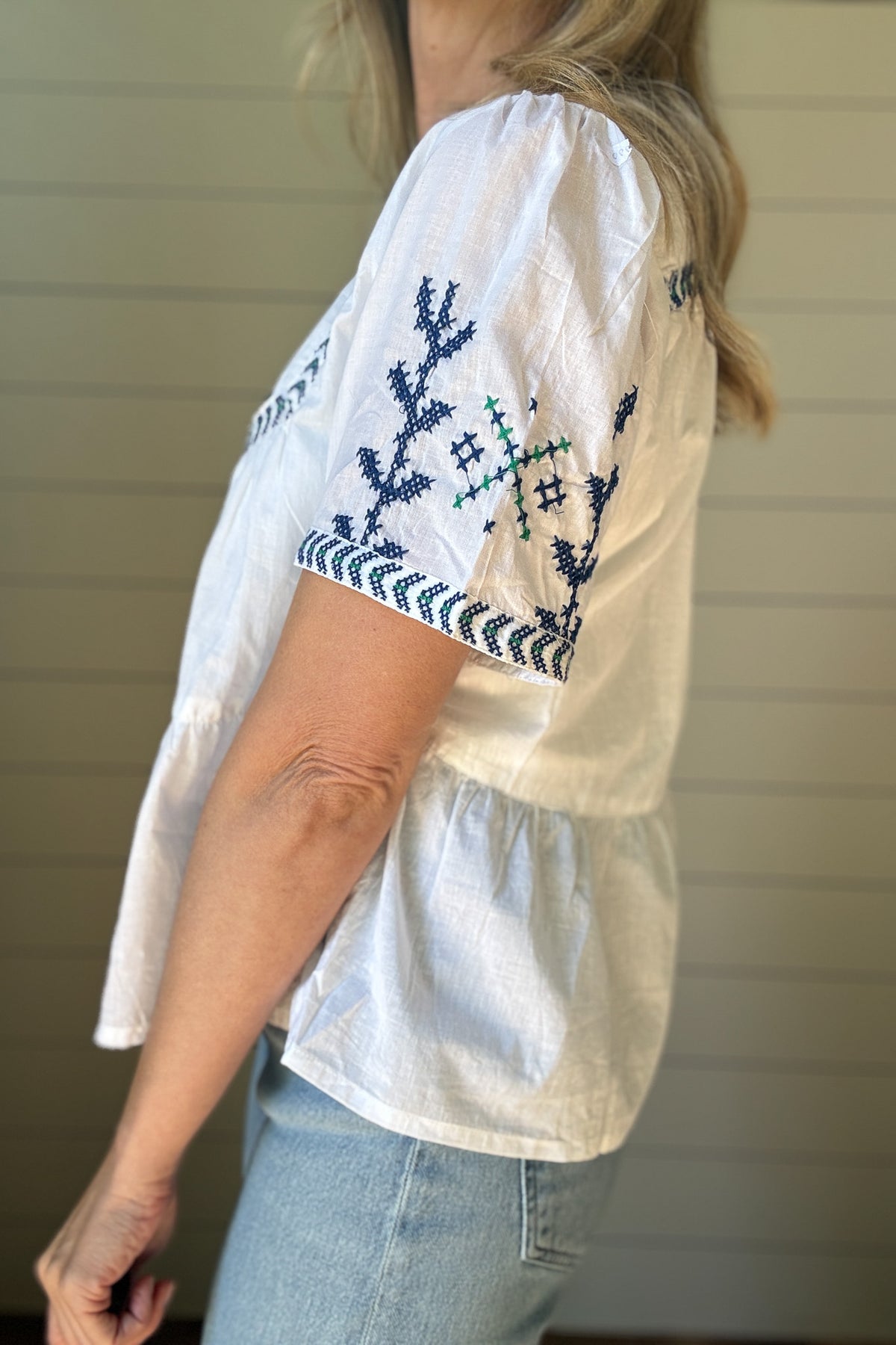This breezy cotton blouse is all about easy charm. Made from 100% cotton, it's lightweight, breathable, and perfect for warm days. The hand-embroidered detail across the neckline, sleeves, and chest adds a special touch, each one slightly unique. It features a relaxed fit with soft gathers for a flowy shape that feels effortless and flattering. The split neckline and short sleeves keep the look casual and cool.