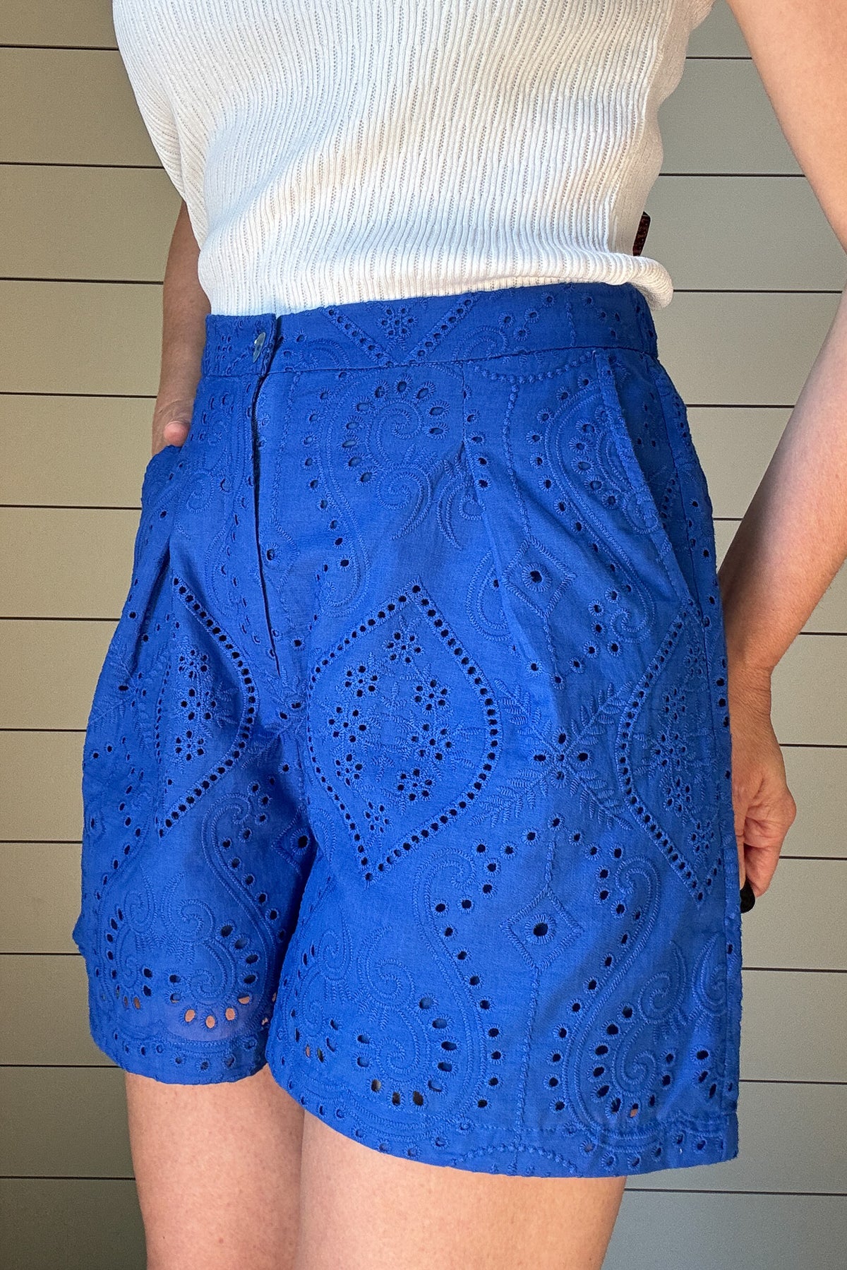 These cobalt blue eyelet shorts are your warm-weather staple with a playful twist. Fully lined for comfort, they offer coverage without bulk. The 4" inseam hits just right for easy movement and everyday wear. A flat front waistband keeps the fit clean, while faux back pockets add a tailored touch without the extra bulk. The waistband is elastic in the back which gives room for movement.
