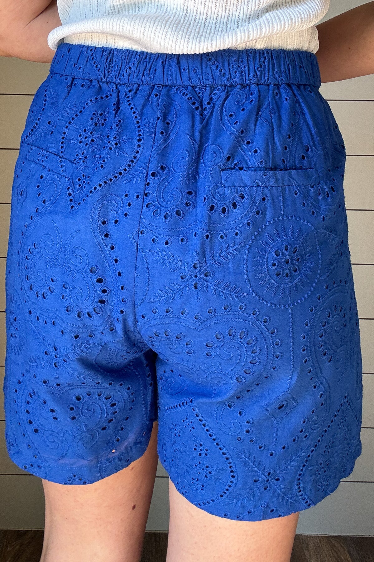 These cobalt blue eyelet shorts are your warm-weather staple with a playful twist. Fully lined for comfort, they offer coverage without bulk. The 4" inseam hits just right for easy movement and everyday wear. A flat front waistband keeps the fit clean, while faux back pockets add a tailored touch without the extra bulk. The waistband is elastic in the back which gives room for movement.