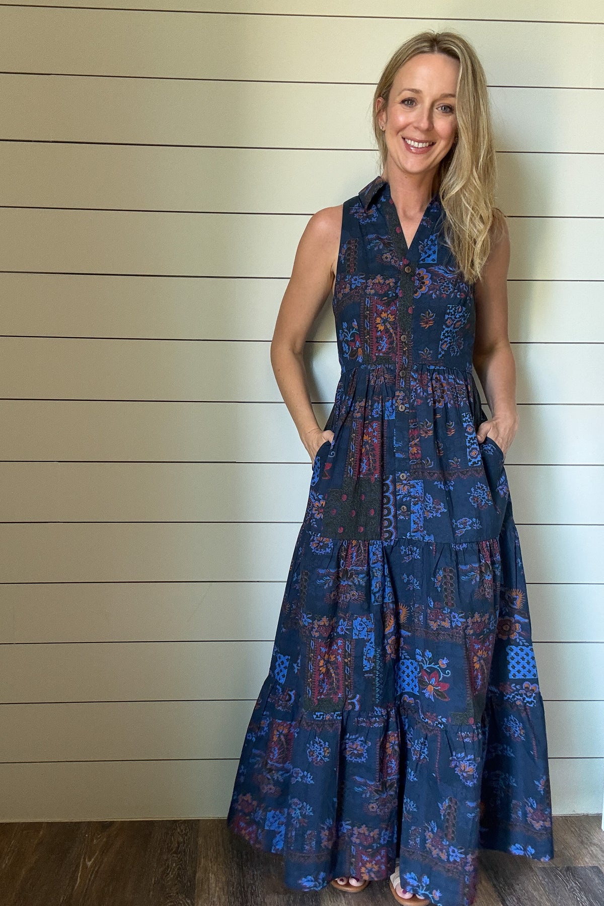Say hello to the Indigo Garden Maxi Dress—an easy favorite for warm days. Made from 100% cotton, this sleeveless maxi is soft, breathable, and light. The button-front bodice and collared neckline give it a clean, polished shape, while the tiered skirt keeps the look relaxed. The printed fabric features a mix of floral and geometric designs in rich indigo, rust, and blue tones. It’s unlined, so it feels cool and comfortable, and yes—it has pockets. Dress it up or down, this one goes wherever your day takes y
