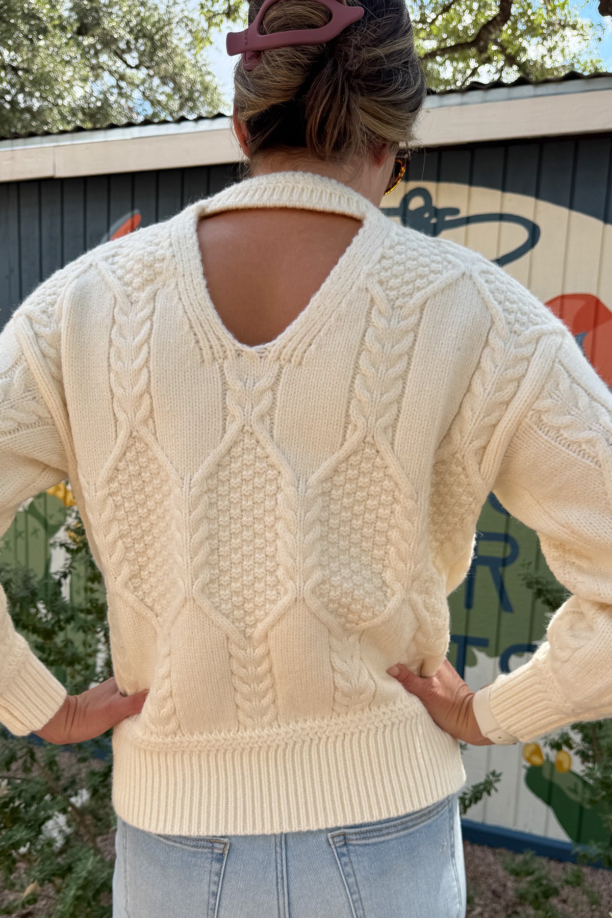 Classic cable knit gets a modern update in this ivory sweater. Designed with intricate knit detailing on the front and sleeves, it features a surprise open-back cutout that adds a chic twist to this timeless style. Soft, cozy, and versatile — it’s the perfect piece for effortless clothing and everyday wear.