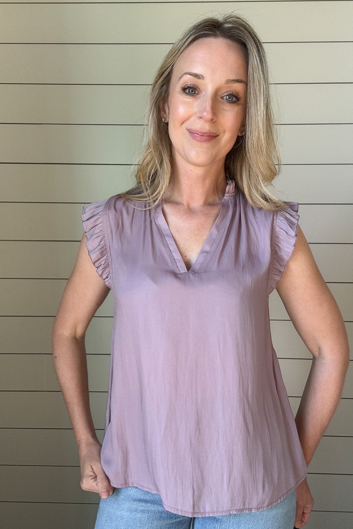 Indulge in luxurious style with our Satin Ruffle Sleeve Blouse. Crafted from lightweight satin fabric, in a warm shade of blushing peach. The v-neck and ruffled shoulders add a touch of sophistication to this sleeveless blouse. Elevate your wardrobe with this exclusive piece.