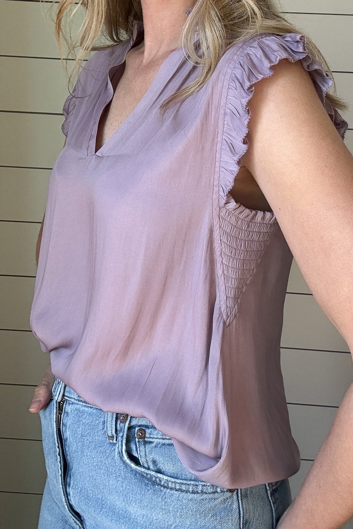 Indulge in luxurious style with our Satin Ruffle Sleeve Blouse. Crafted from lightweight satin fabric, in a warm shade of blushing peach. The v-neck and ruffled shoulders add a touch of sophistication to this sleeveless blouse. Elevate your wardrobe with this exclusive piece.