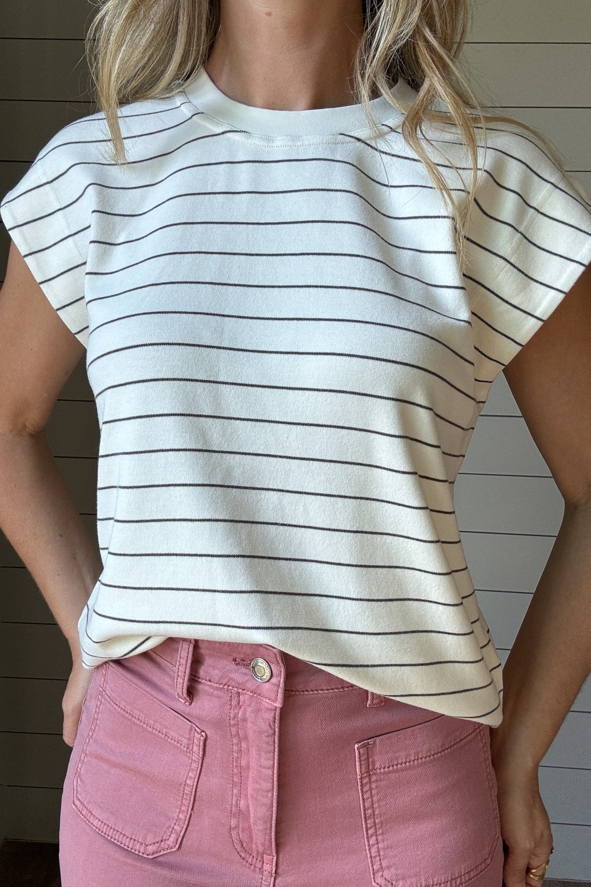  This striped knit top is the definition of easy, everyday style. Made from a soft, medium-weight knit, it drapes beautifully while keeping its shape. The classic ivory base with thin black stripes gives it a timeless look, and the relaxed cap sleeves add just the right amount of detail. Perfect on its own or layered under a jacket, it’s the kind of piece you’ll reach for all year long.