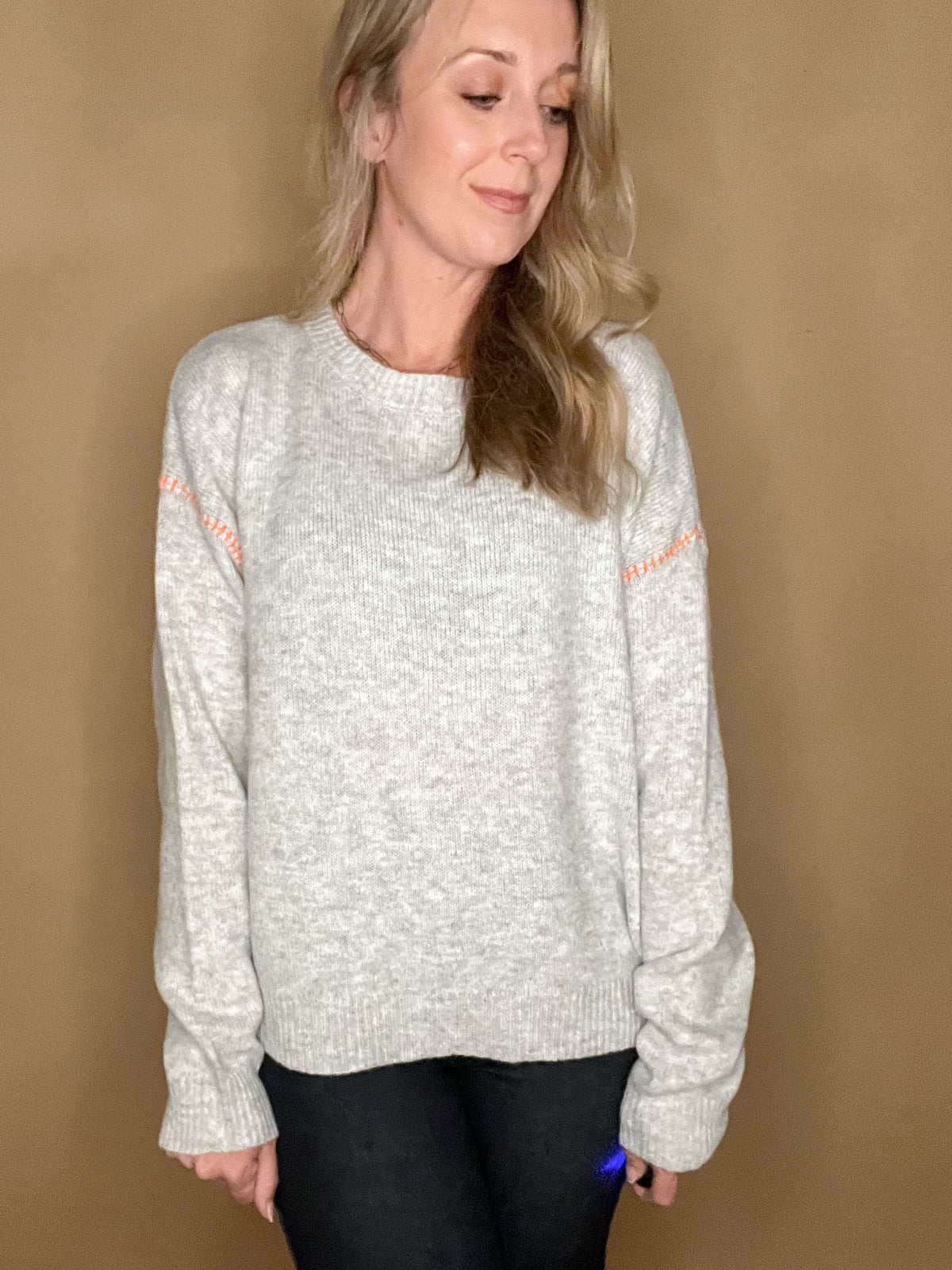 This Pop of Orange Sweater will make a chic statement this season. Its soft gray hue and exquisite orange stitching create a cozy yet refined look perfect for any occasion. The slightly oversized silhouette adds effortless elegance to your wardrobe.