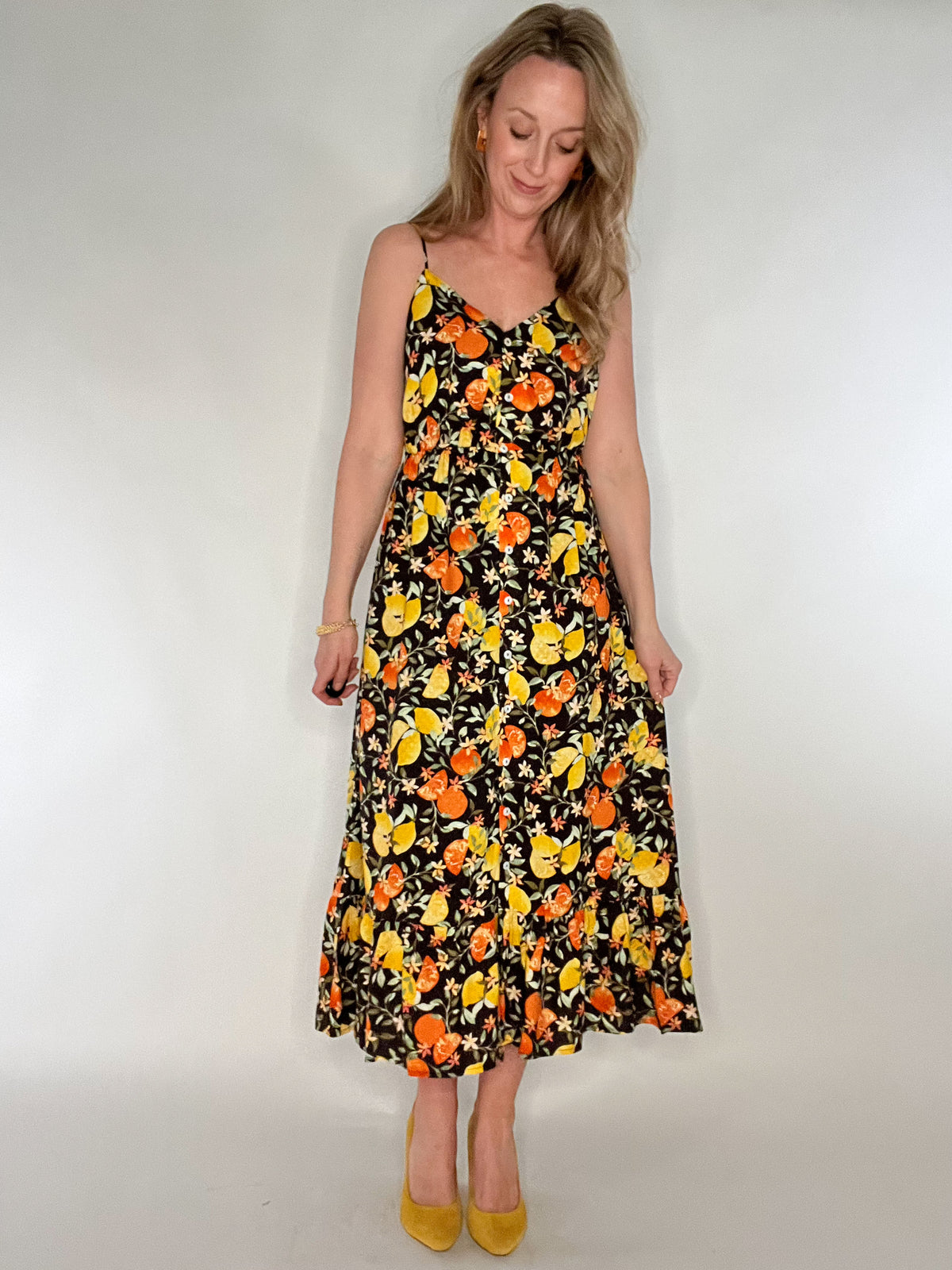 Make a bold statement in our Citrus Punch Maxi Dress. Featuring a playful citrus print, this adjustable spaghetti strap dress is perfect for any occasion. The tiered skirt adds a feminine touch while the button front and elastic waist provide a flattering fit. Fully lined to the knees for ultimate comfort and style.
