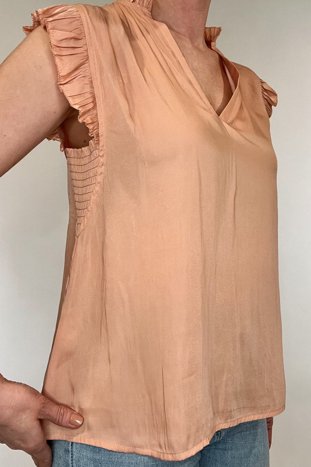 Indulge in luxurious style with our Satin Ruffle Sleeve Blouse. Crafted from lightweight satin fabric, it comes in two soft and feminine colors - lavender and peach. The v-neck and ruffled shoulders add a touch of sophistication to this sleeveless blouse. Elevate your wardrobe with this exclusive piece.