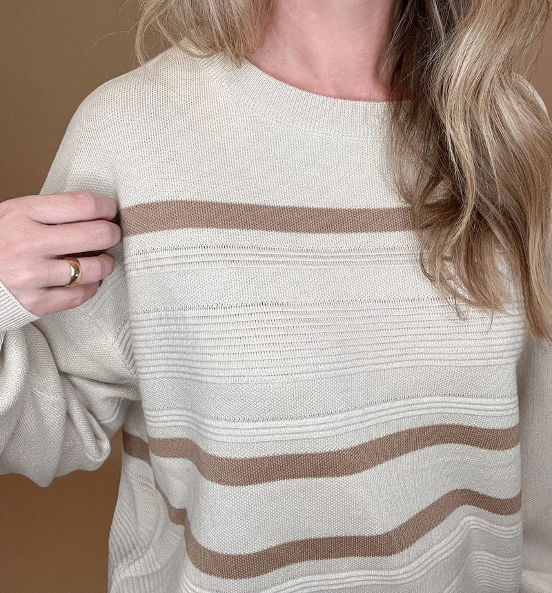 Relish the subtle sophistication of this exquisitely crafted Subtle Stripe Sweater. Crafted from a lustrous blend of eco-friendly fabric, this timeless piece features a creamy ecru and tan striped design and delicate round neckline. The slightly longer fit creates an effortless silhouette that pairs perfectly with denim, making it the perfect everyday piece.