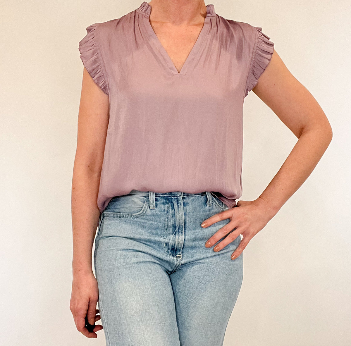 Indulge in luxurious style with our Satin Ruffle Sleeve Blouse. Crafted from lightweight satin fabric, it comes in two soft and feminine colors - lavender and peach. The v-neck and ruffled shoulders add a touch of sophistication to this sleeveless blouse. Elevate your wardrobe with this exclusive piece.