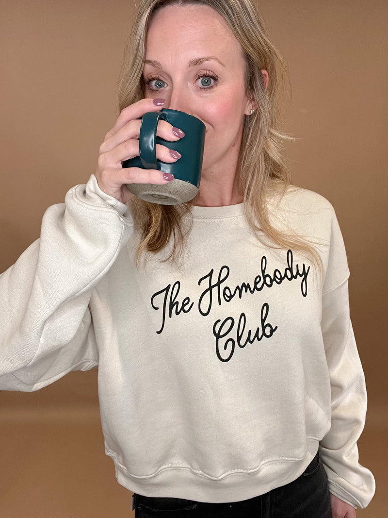 This Homebody Club Sweatshirt is a luxurious statement piece for those cozy days at home. Crafted from cozy cream fabric and black print, this sweatshirt is perfect for you or for a special someone. Wearing it will remind you that it's always homebody season.