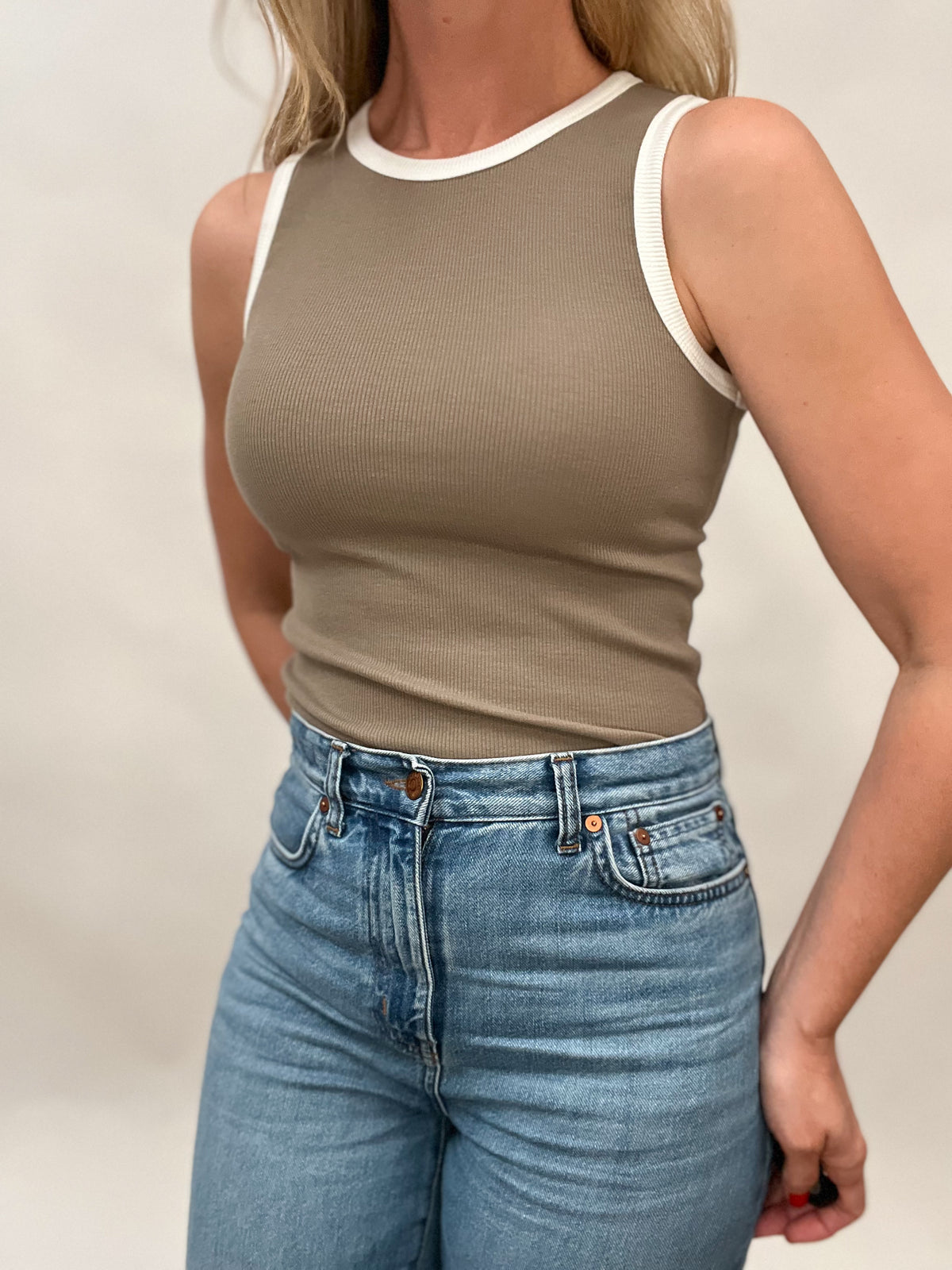 Get ready for summer vibes with our sandy shores tan fitted ribbed sleeveless tank! The bright white edging on the neck and sleeves adds a fresh pop to this effortlessly stylish piece. Perfect for pairing with your favorite denim shorts or a flowy skirt for a relaxed and chic look.