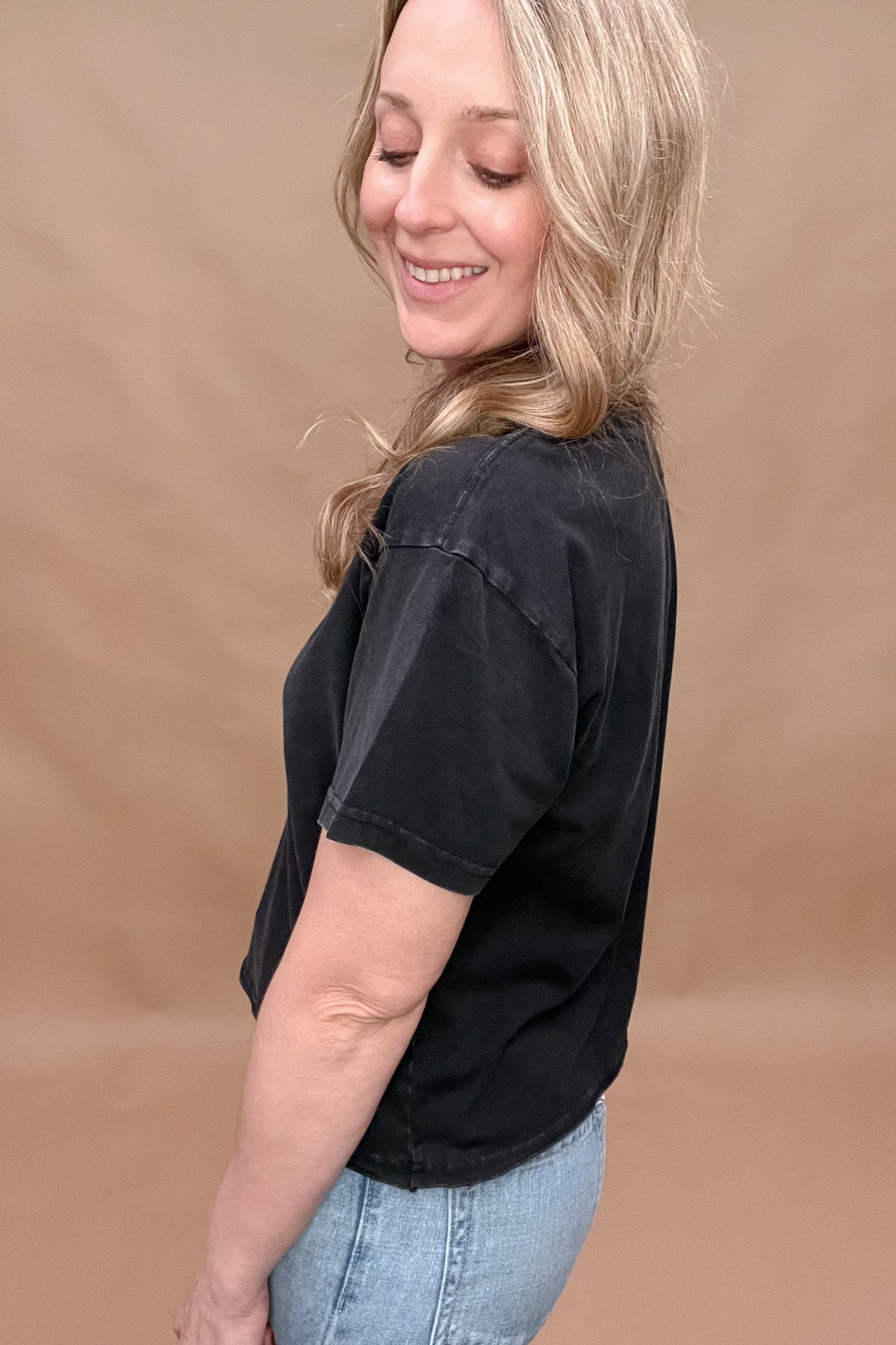 This black mineral washed tee features a slight crop and a raw bottom hem, creating an effortless look that hits at the top of the hips. Perfectly paired with denim for a stylish and comfortable outfit.