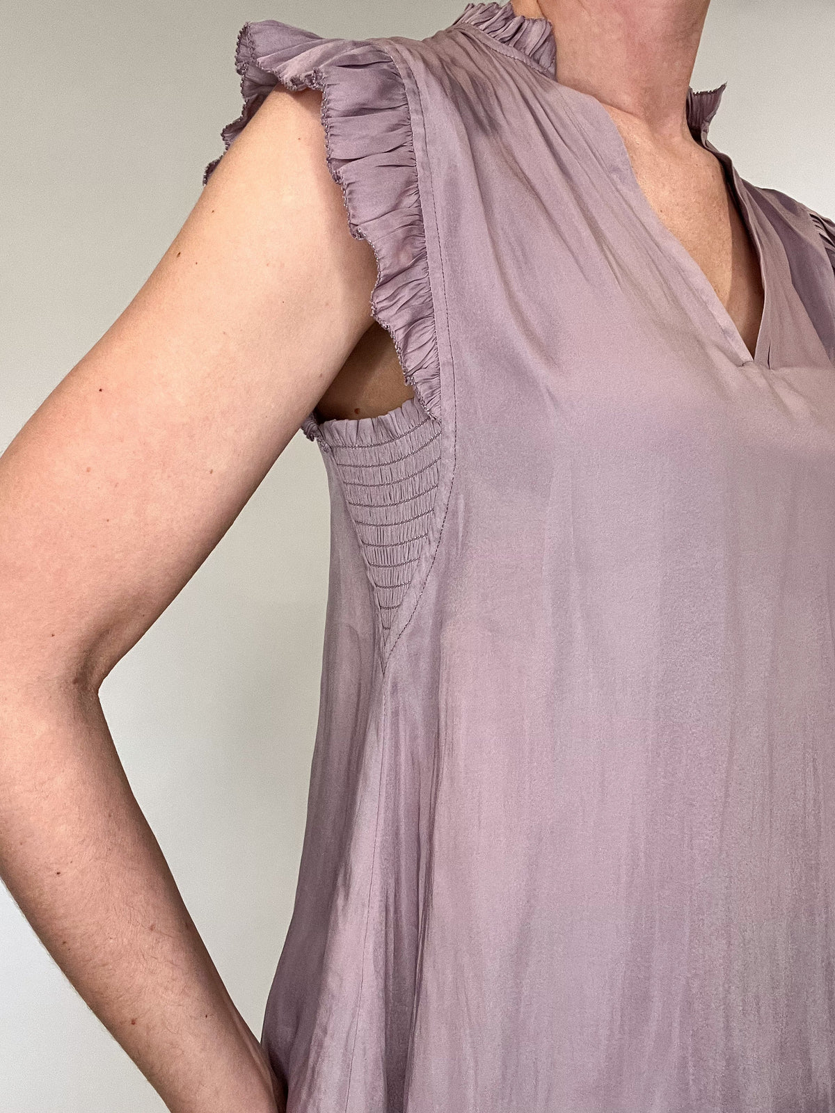 Indulge in luxurious style with our Satin Ruffle Sleeve Blouse. Crafted from lightweight satin fabric, it comes in two soft and feminine colors - lavender and peach. The v-neck and ruffled shoulders add a touch of sophistication to this sleeveless blouse. Elevate your wardrobe with this exclusive piece.