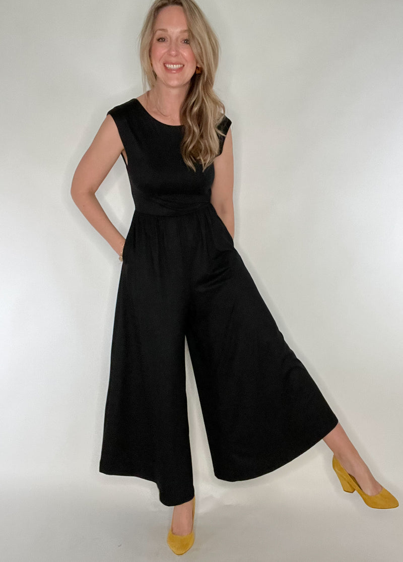 The Illusive Jumper is a versatile and comfortable piece that combines the elegance of a dress with the convenience of a romper. Made with luxurious black jersey fabric, it features angled hem, pockets, and a low cut back with wide straps for bra support. The fitted bodice flares at the waist for a flattering silhouette. Elevate your style with this sophisticated and artful piece.