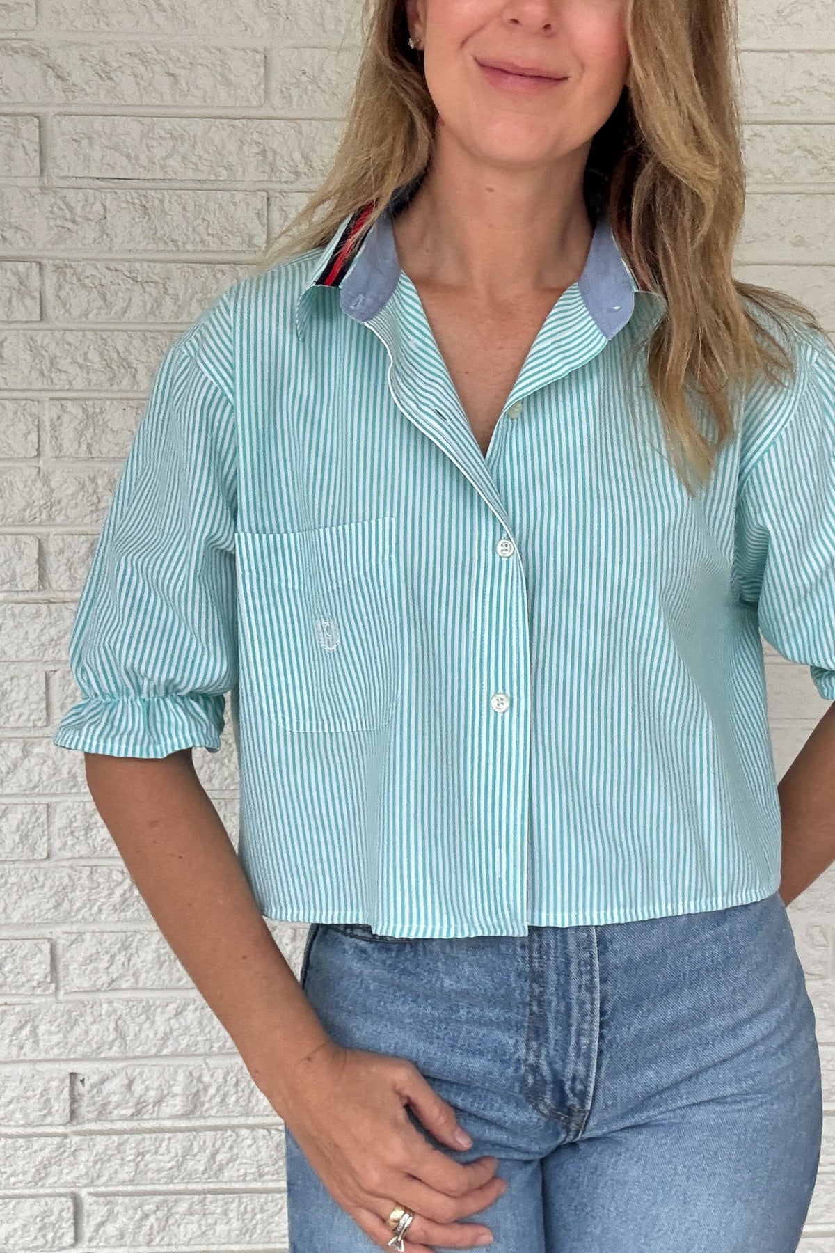 Front photo:
VonVie Harlow aqua and white striped cropped button down shirt with chest pocket, puff sleeves, and ruffled cuffs

Back photo:
Back view of VonVie Harlow aqua striped shirt with open back and red and navy ribbon ties