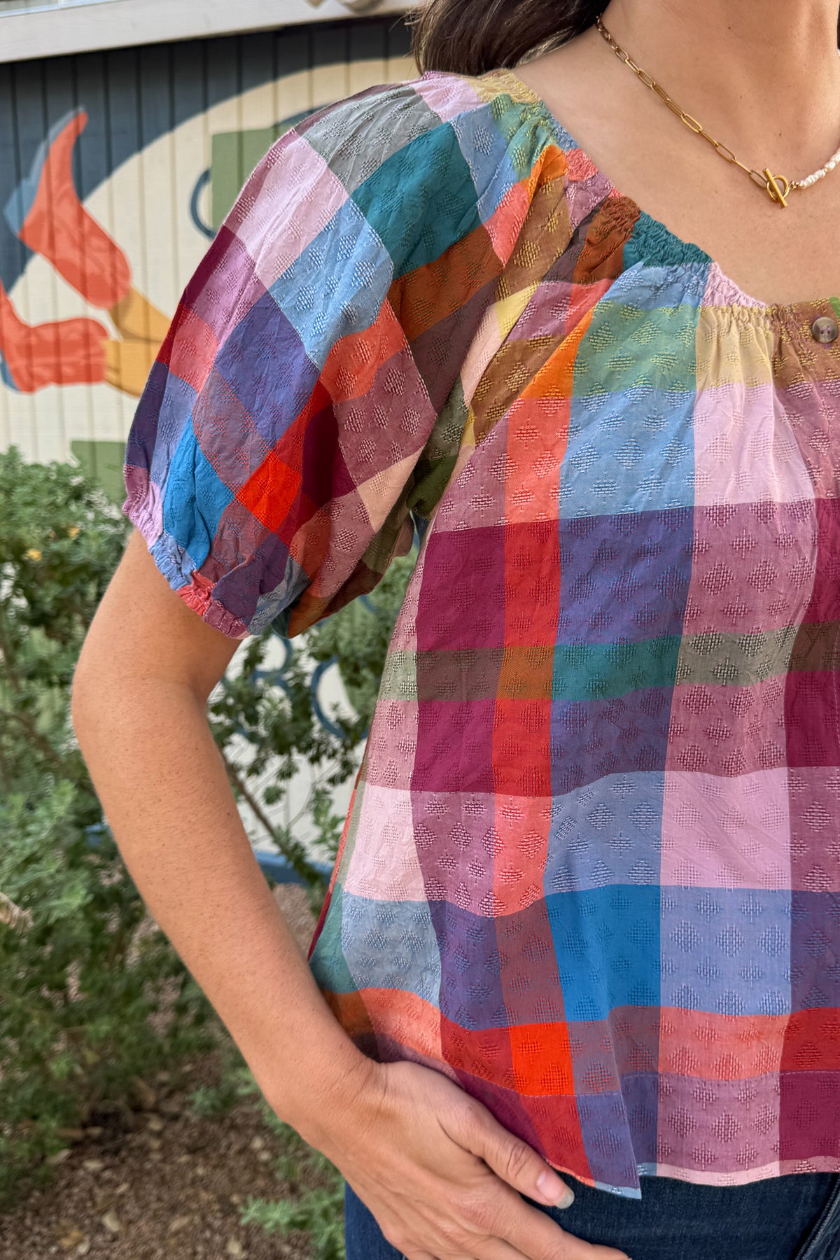Colorful plaid cotton puff sleeve top with a relaxed fit and button neckline, available at Cotton & Cashmere in Blanco, Texas.