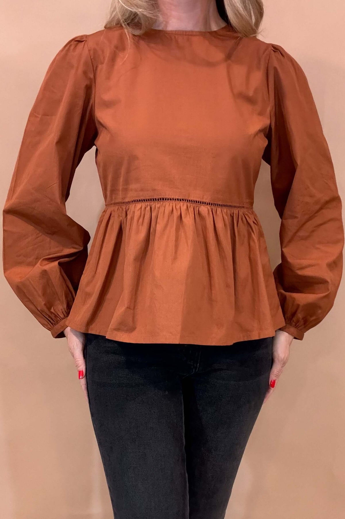 Our Lauren Babydoll Top is perfect for dressing up any look. It features a fitted bodice that flares out below the waist, accented with ladder lace trim at the waist seam. Made from soft poplin with an easy to slip on button back, it offers just enough structure to hold its shape, and it includes a slight puff sleeve for added charm.