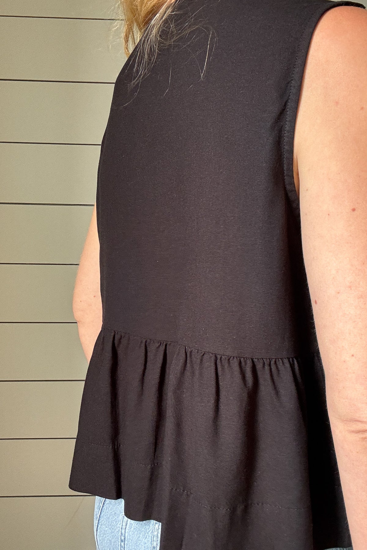 Sweet meets chic in this black top with feminine details and an easy fit. Featuring two soft bow ties at the neckline, it brings just the right touch of charm. The babydoll-style seam falls just below the ribs, giving a flattering shape without clinging. Flowy and lightweight, it moves beautifully and pairs well with denim, linen pants, or shorts. The black color keeps it classic while the silhouette adds interest and softness. An easy pick when you want something a little special without trying too hard.