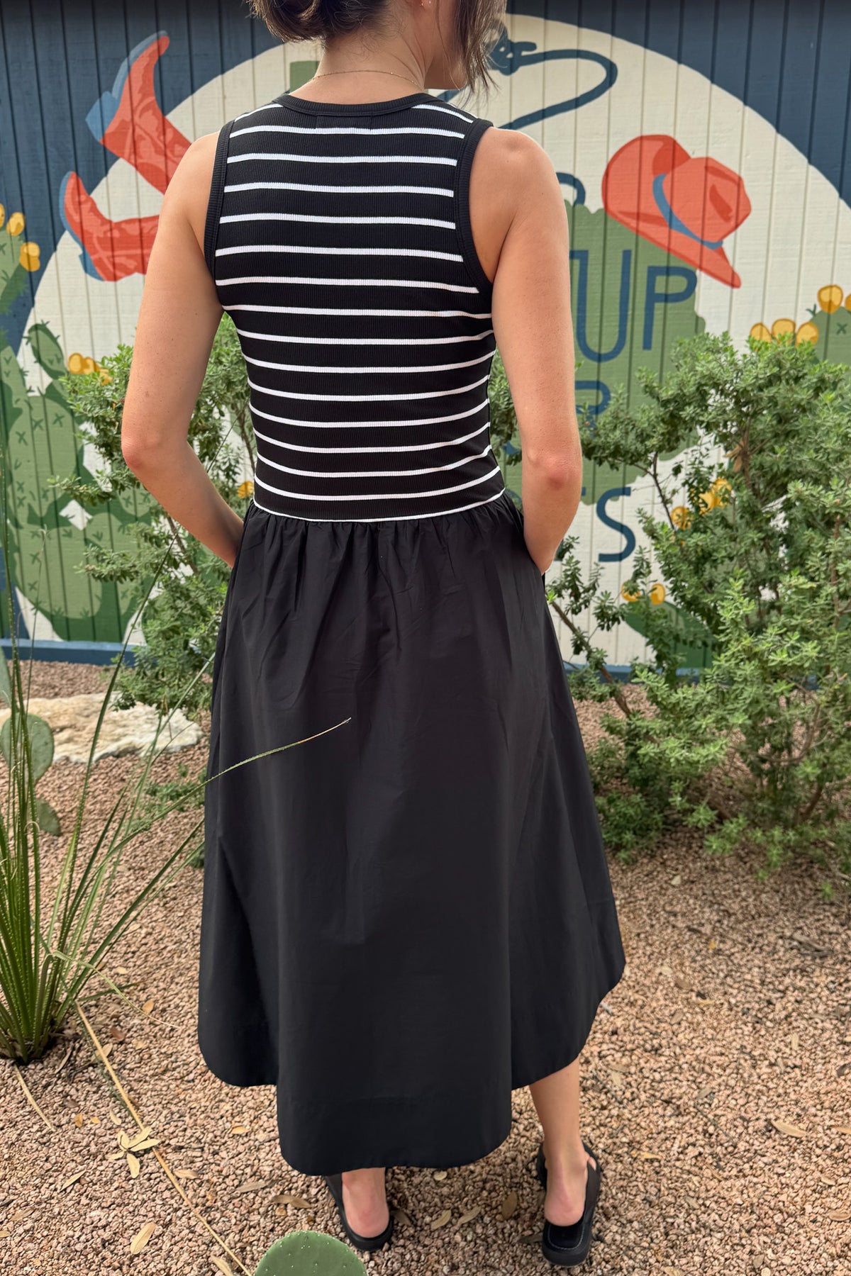 Back view of a women’s black midi dress with a striped ribbed tank bodice, fitted waist and gathered full-length skirt.