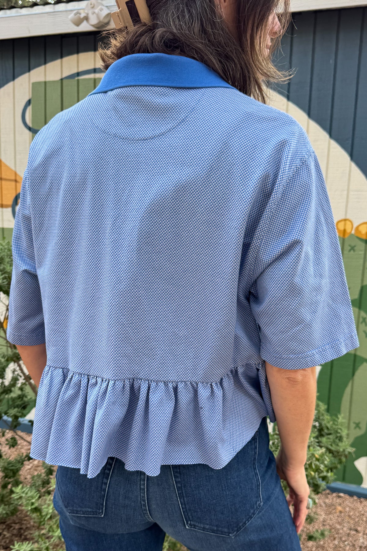 Women’s blue upcycled polo top by VonVie featuring a cropped relaxed fit and signature feminine ruffle hem.