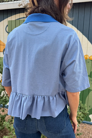 Women’s blue upcycled polo top by VonVie featuring a cropped relaxed fit and signature feminine ruffle hem.