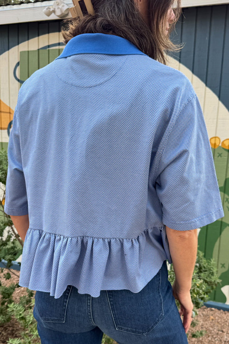Women’s blue upcycled polo top by VonVie featuring a cropped relaxed fit and signature feminine ruffle hem.