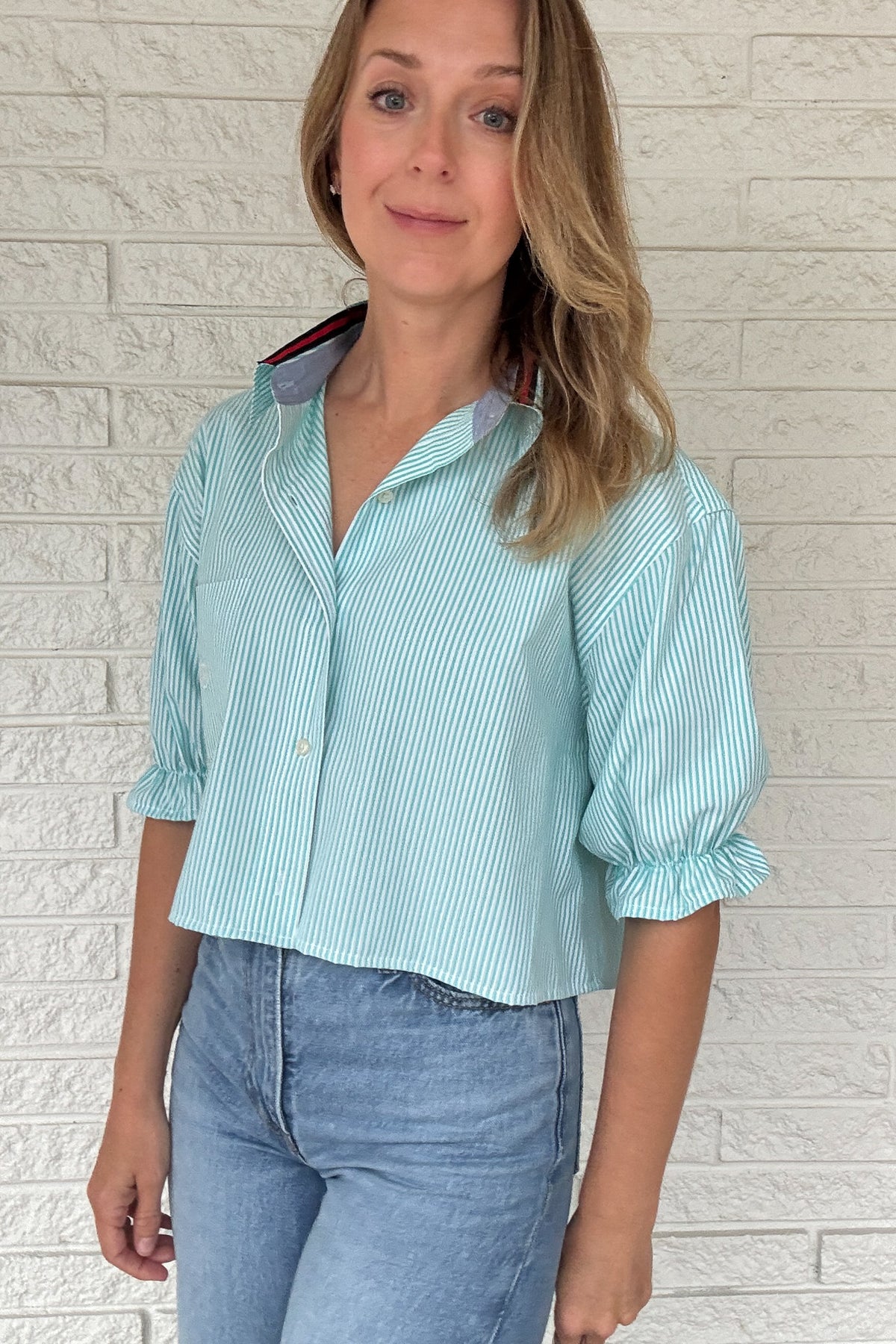 Front photo:
VonVie Harlow aqua and white striped cropped button down shirt with chest pocket, puff sleeves, and ruffled cuffs

Back photo:
Back view of VonVie Harlow aqua striped shirt with open back and red and navy ribbon ties