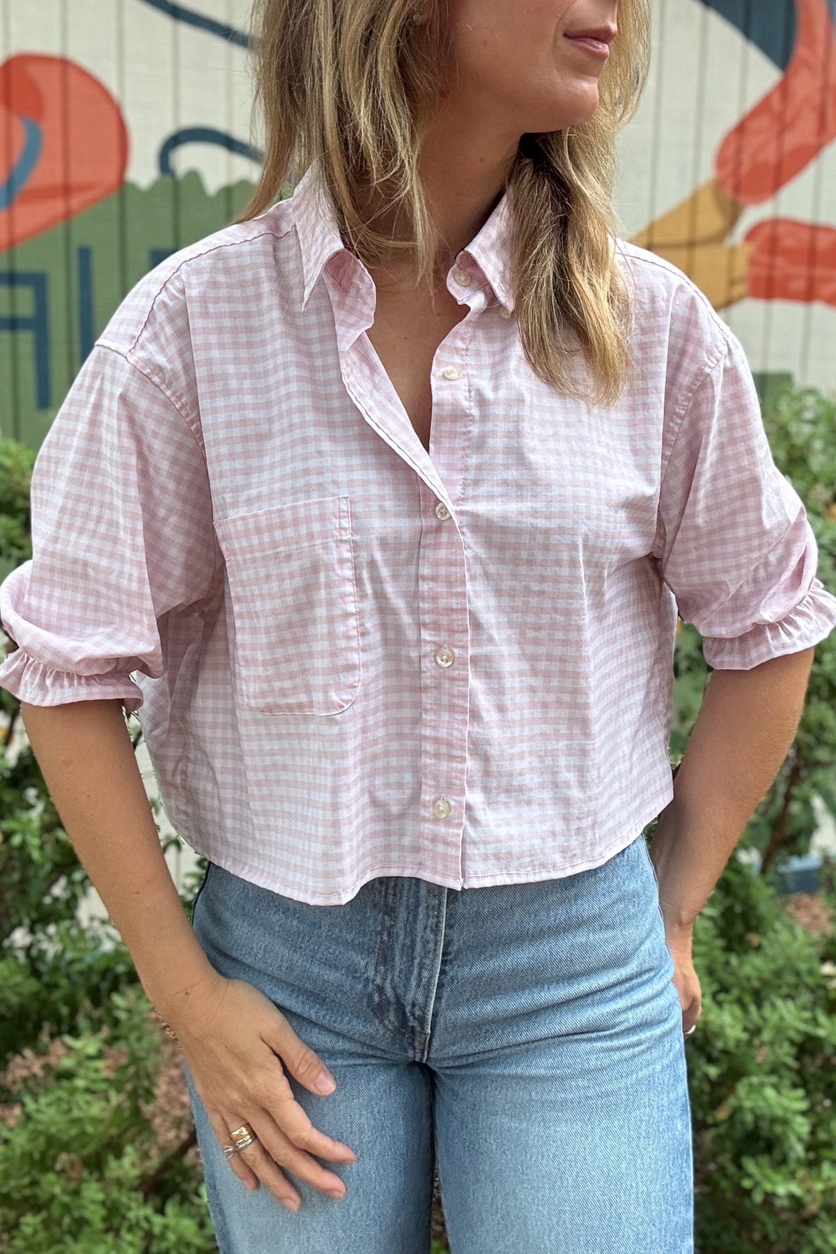 Back photo:
Back view of VonVie Harlow pink gingham cropped shirt with open back and red and navy ribbon ties

Side photo:
Side view of VonVie Harlow pink gingham shirt with puff sleeves, ruffled cuffs, and a relaxed cropped fit