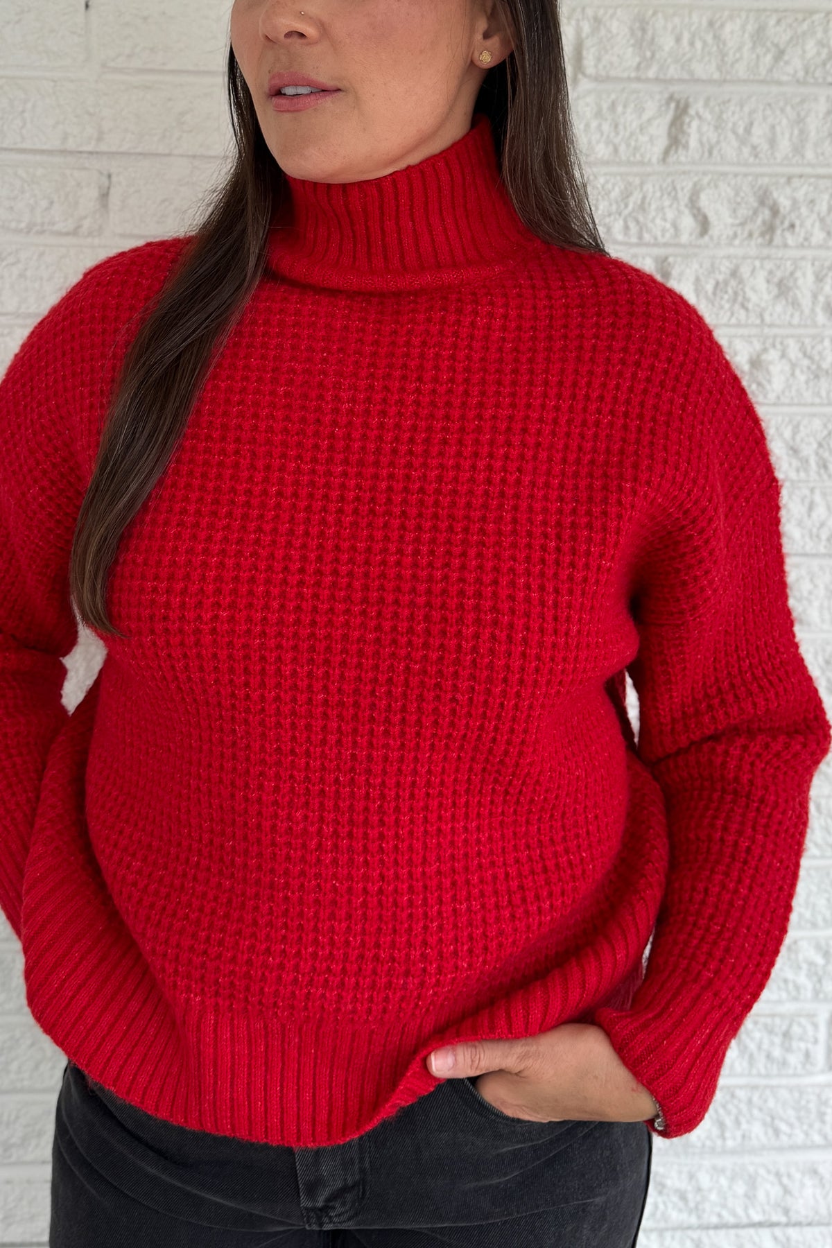 This bold red oversized sweater brings warmth and style together in one easy piece. Knitted in a soft, textured “square” weave, it features a cozy stand-up collar and ribbed finishes that keep the look clean and structured. Perfect for pairing with denim or a skirt for effortless everyday wear.