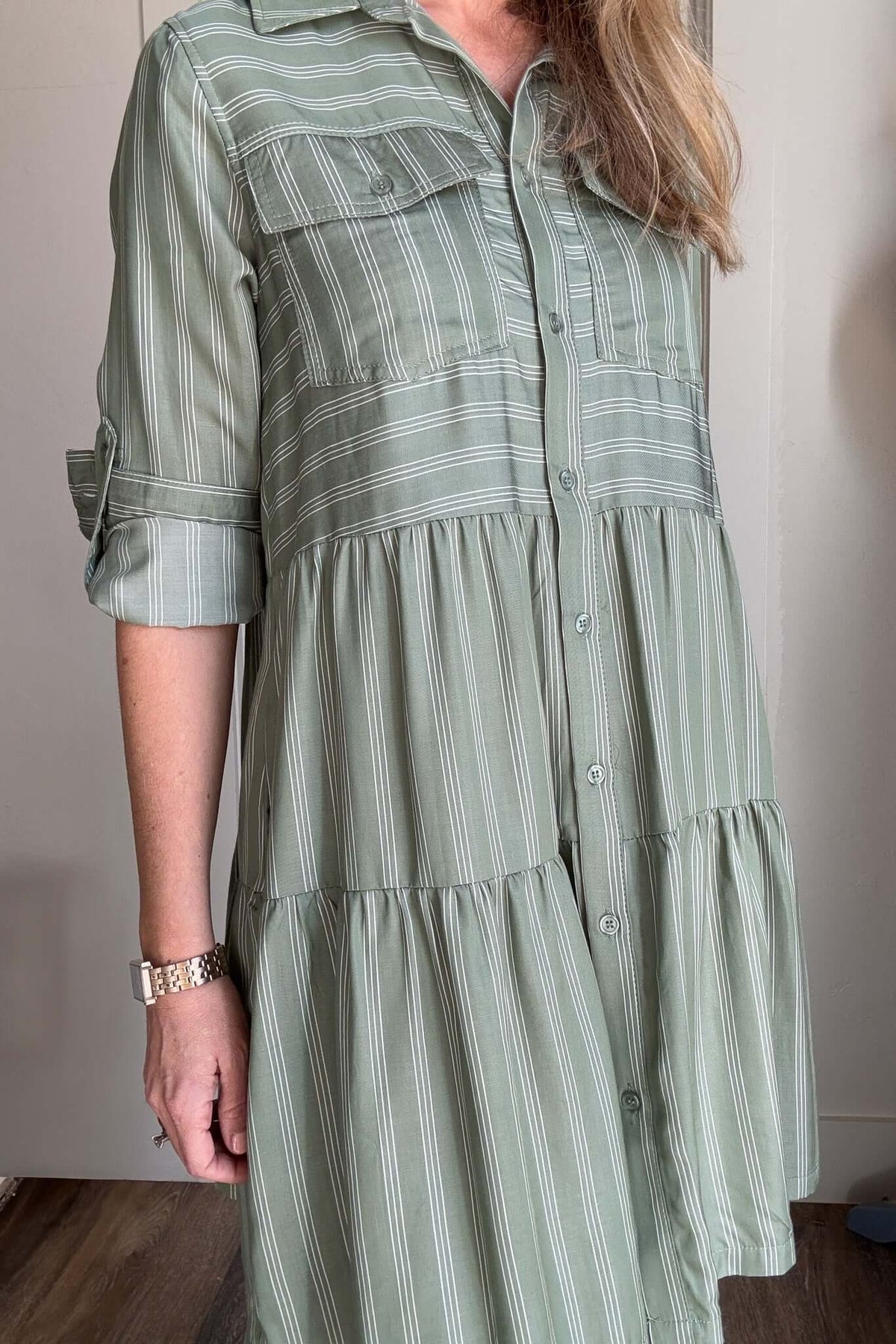 Introducing our Breezy Dress, the epitome of effortless elegance.

Made from silky Tencel fabric, this button up tiered dress features a classic white pinstripe design and functional buttoned front pockets.

With the ability to roll and secure the sleeves with a button tab, it's the perfect dress for any occasion.&nbsp;