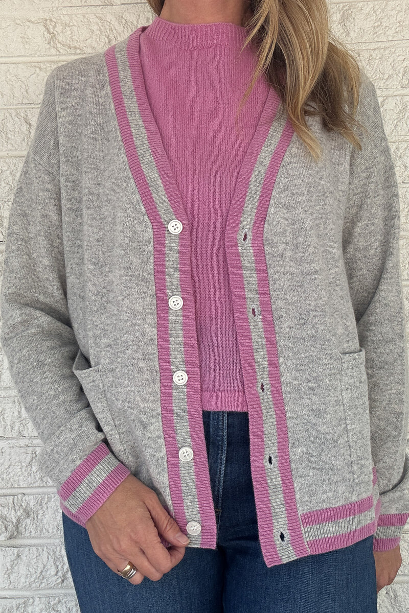 Luxury meets everyday ease in this 100% cashmere cardigan. The soft heather grey body is accented with bold pink and grey striped trim, giving a classic silhouette a modern pop of color. Lightweight yet warm, it’s the perfect piece for layering — an elevated staple for effortless clothing and everyday wear.