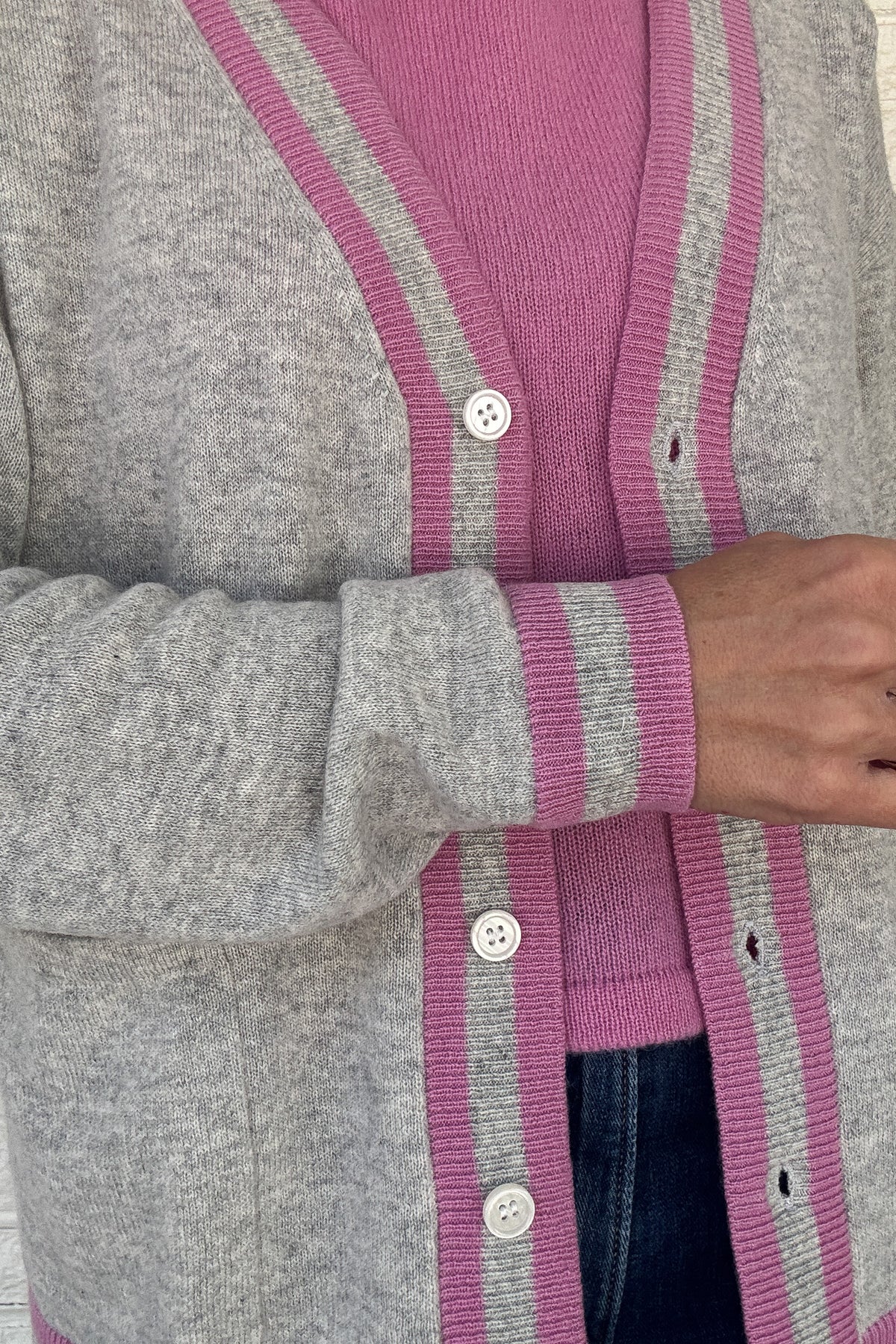 Luxury meets everyday ease in this 100% cashmere cardigan. The soft heather grey body is accented with bold pink and grey striped trim, giving a classic silhouette a modern pop of color. Lightweight yet warm, it’s the perfect piece for layering — an elevated staple for effortless clothing and everyday wear.