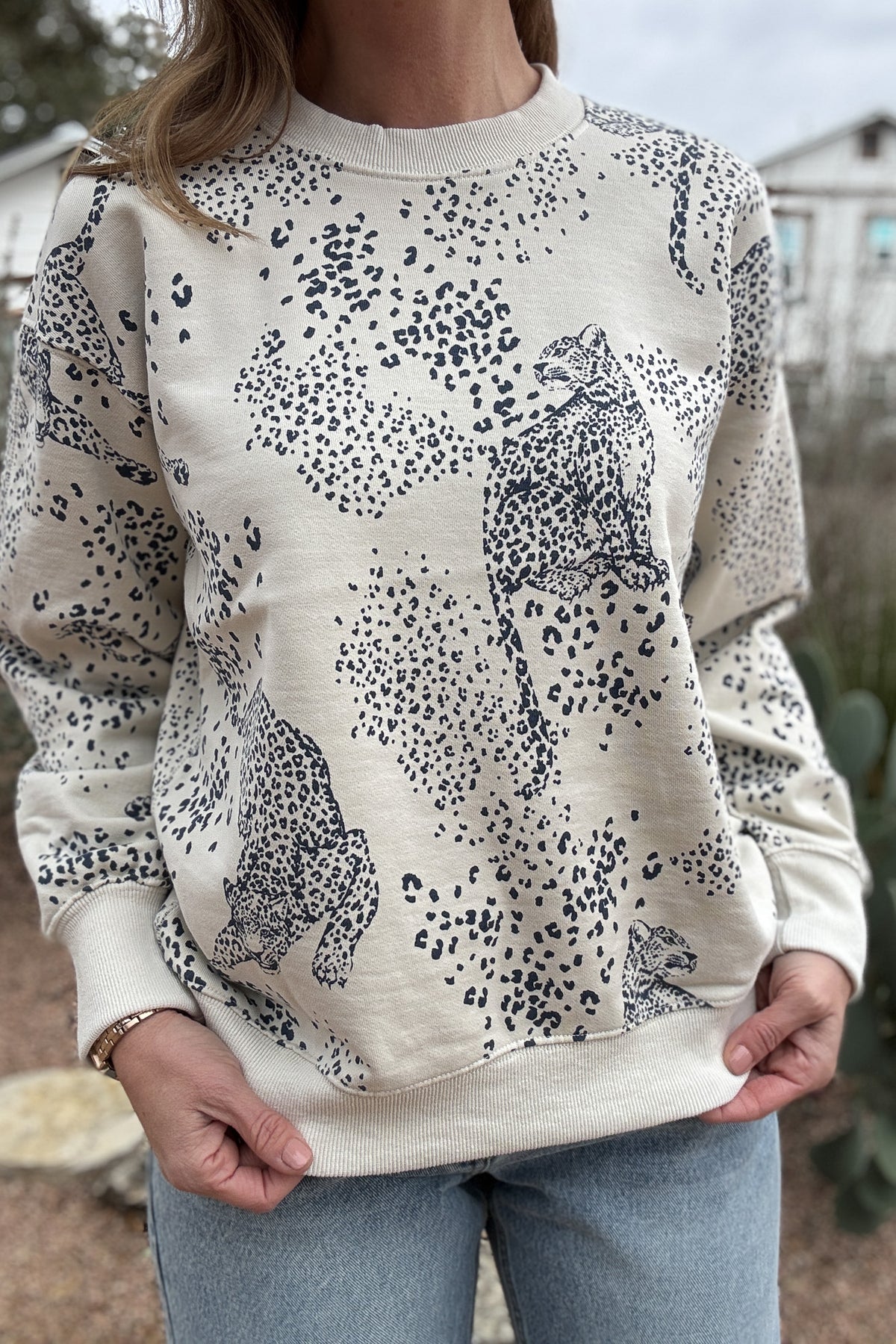 This cream sweatshirt features a soft neutral base with a subtle leopard print and cheetah motif throughout. Easy, relaxed, and made for everyday wear, it’s the kind of piece you’ll reach for on repeat. Perfect with denim, joggers, or layered under a jacket for effortless style.