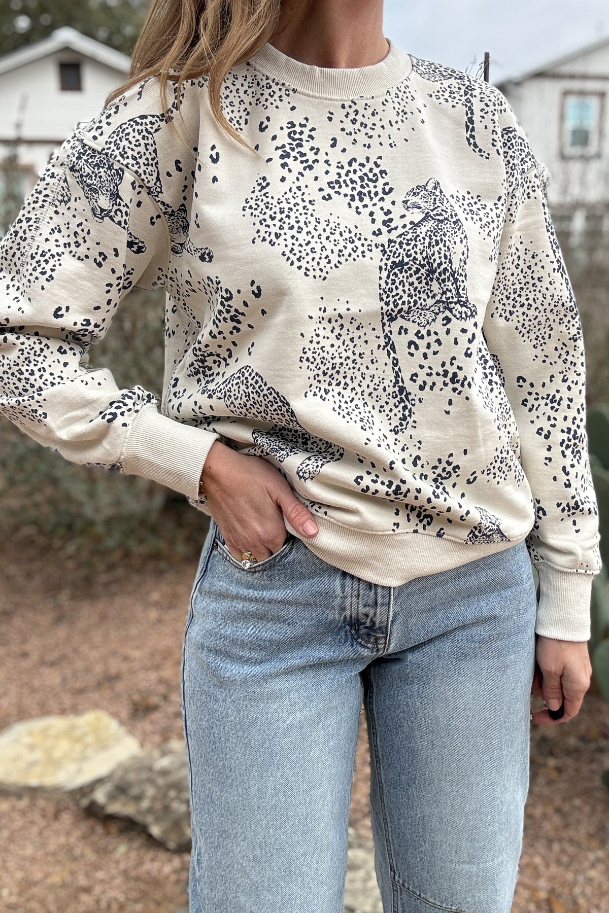 This cream sweatshirt features a soft neutral base with a subtle leopard print and cheetah motif throughout. Easy, relaxed, and made for everyday wear, it’s the kind of piece you’ll reach for on repeat. Perfect with denim, joggers, or layered under a jacket for effortless style.