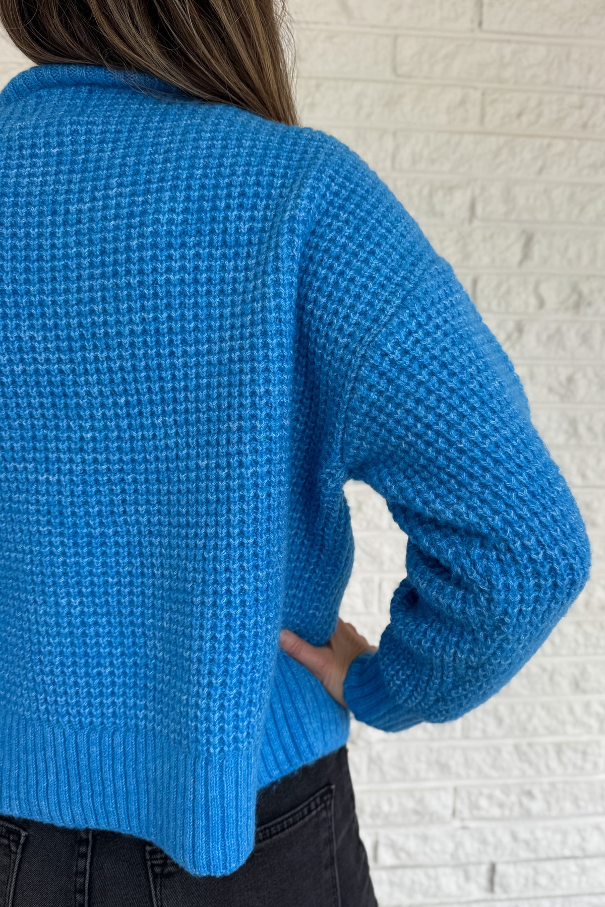 This bold blue oversized sweater brings warmth and style together in one easy piece. Knitted in a soft, textured “square” weave, it features a cozy stand-up collar and ribbed finishes that keep the look clean and structured. Perfect for pairing with denim or a skirt for effortless everyday wear.