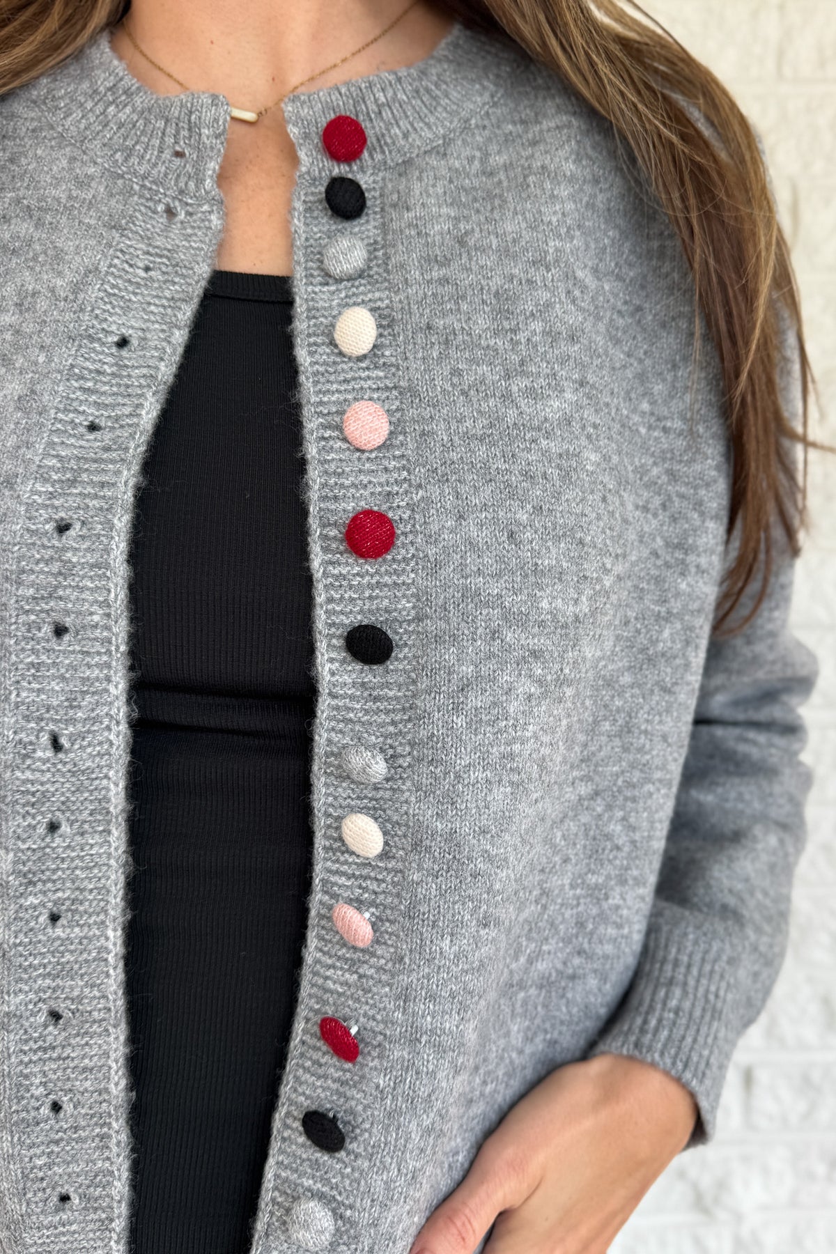 Designed in Spain, this soft grey cardigan brings a fun twist to a timeless classic. The colorful knit-covered buttons add a playful pop while keeping the look polished. It’s a cozy, easy-to-wear piece that pairs effortlessly with denim or trousers for everyday style.