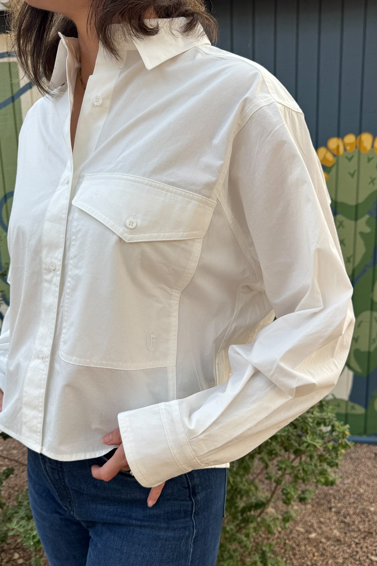 Relaxed white cotton shirt for women featuring a utility-style pocket, dropped shoulders, and slightly cropped length.