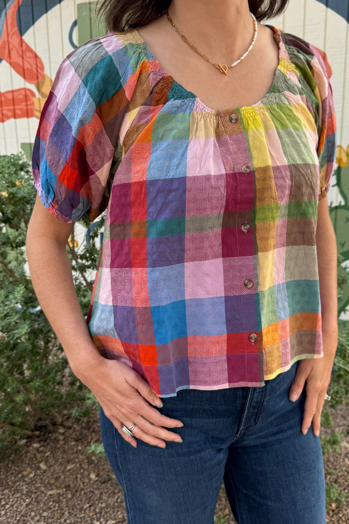 Women’s colorful plaid cotton dobby top with a gathered neckline, button-front detail, and short puff sleeves.