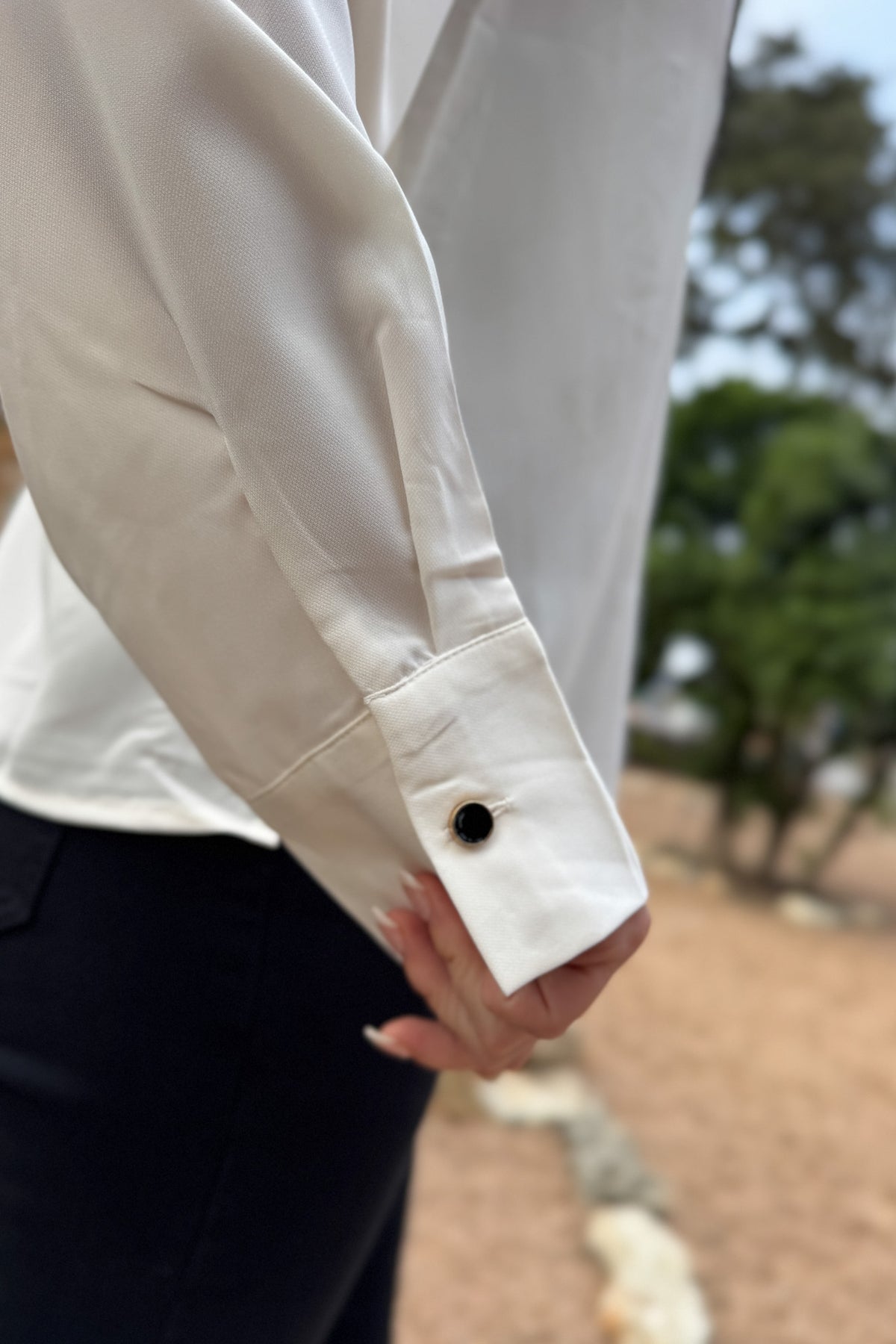 A classic button-up with subtle contrast detailing. This blouse features a clean front accented with black scalloped trim and matching buttons for a polished finish. Lightweight with a soft drape, it transitions easily from work to dinner and layers well under blazers or jackets.