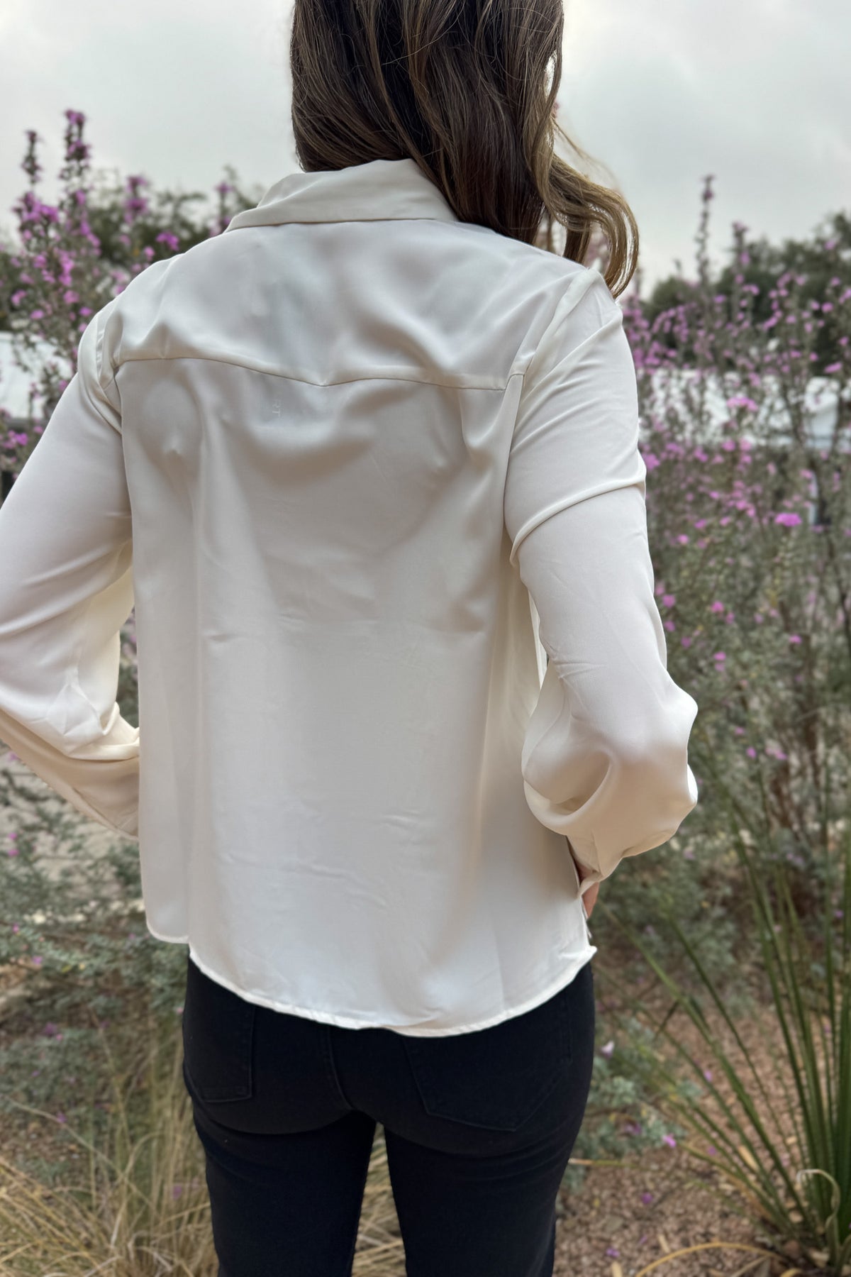 A classic button-up with subtle contrast detailing. This blouse features a clean front accented with black scalloped trim and matching buttons for a polished finish. Lightweight with a soft drape, it transitions easily from work to dinner and layers well under blazers or jackets.