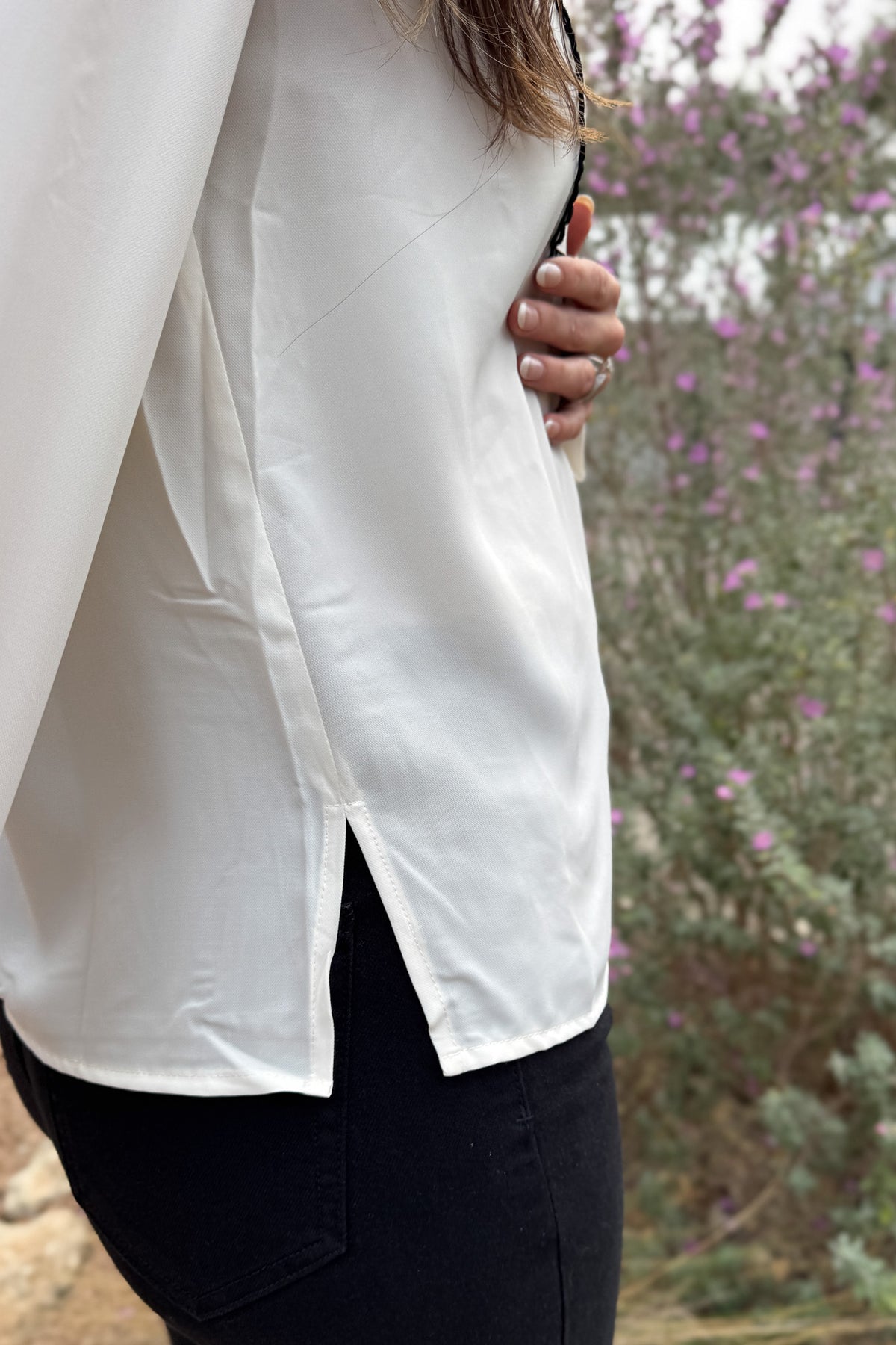 A classic button-up with subtle contrast detailing. This blouse features a clean front accented with black scalloped trim and matching buttons for a polished finish. Lightweight with a soft drape, it transitions easily from work to dinner and layers well under blazers or jackets.