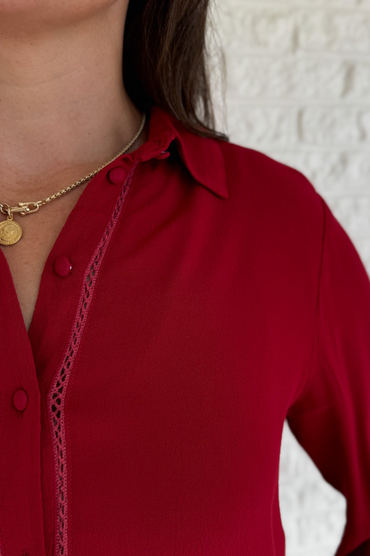 &nbsp;This rich red blouse delivers classic style with a subtle feminine touch. Designed in soft 100% viscose, it features delicate lace trim along the button placket and a flattering v-neckline with a small collar.