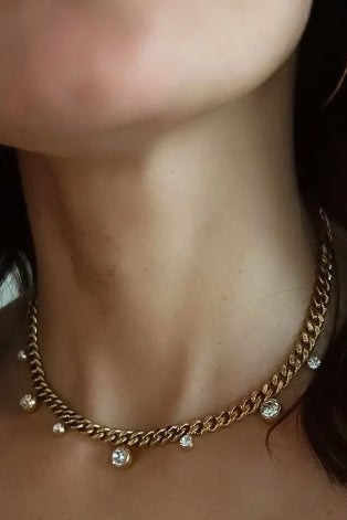 Gold chain necklace with small round pendants on a person's neck